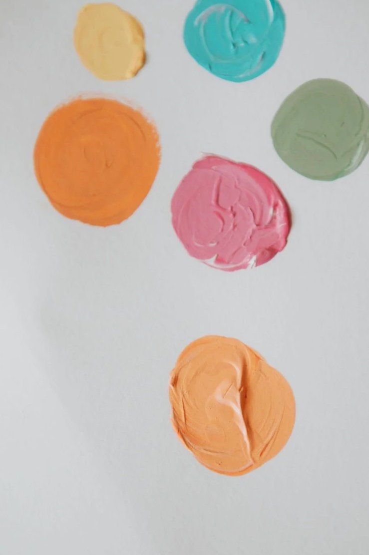 Six colorful blobs of modeling clay on a white background in yellow, teal, green, pink, orange, and peach colors.