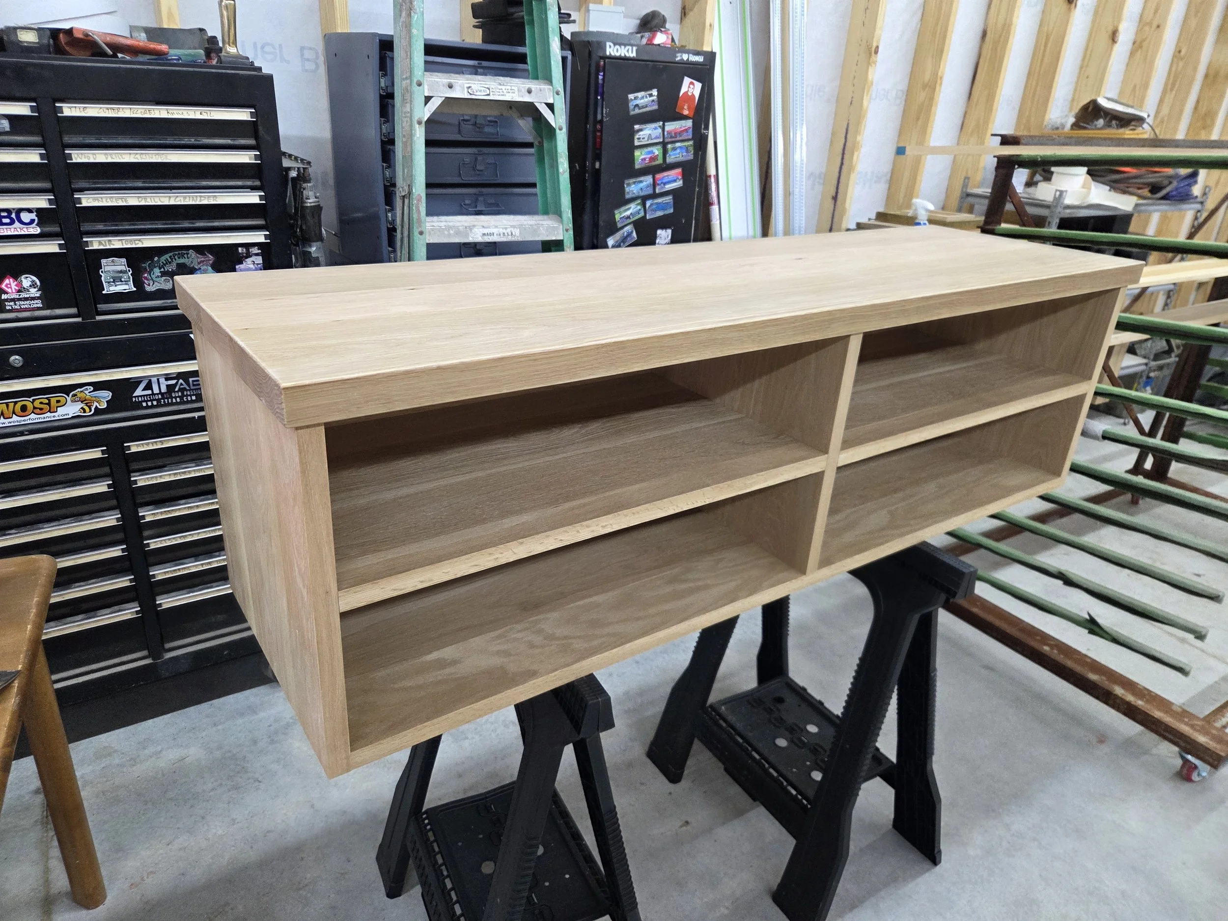 A wooden shelf being assembled in a workshop surrounded by various tools and materials.