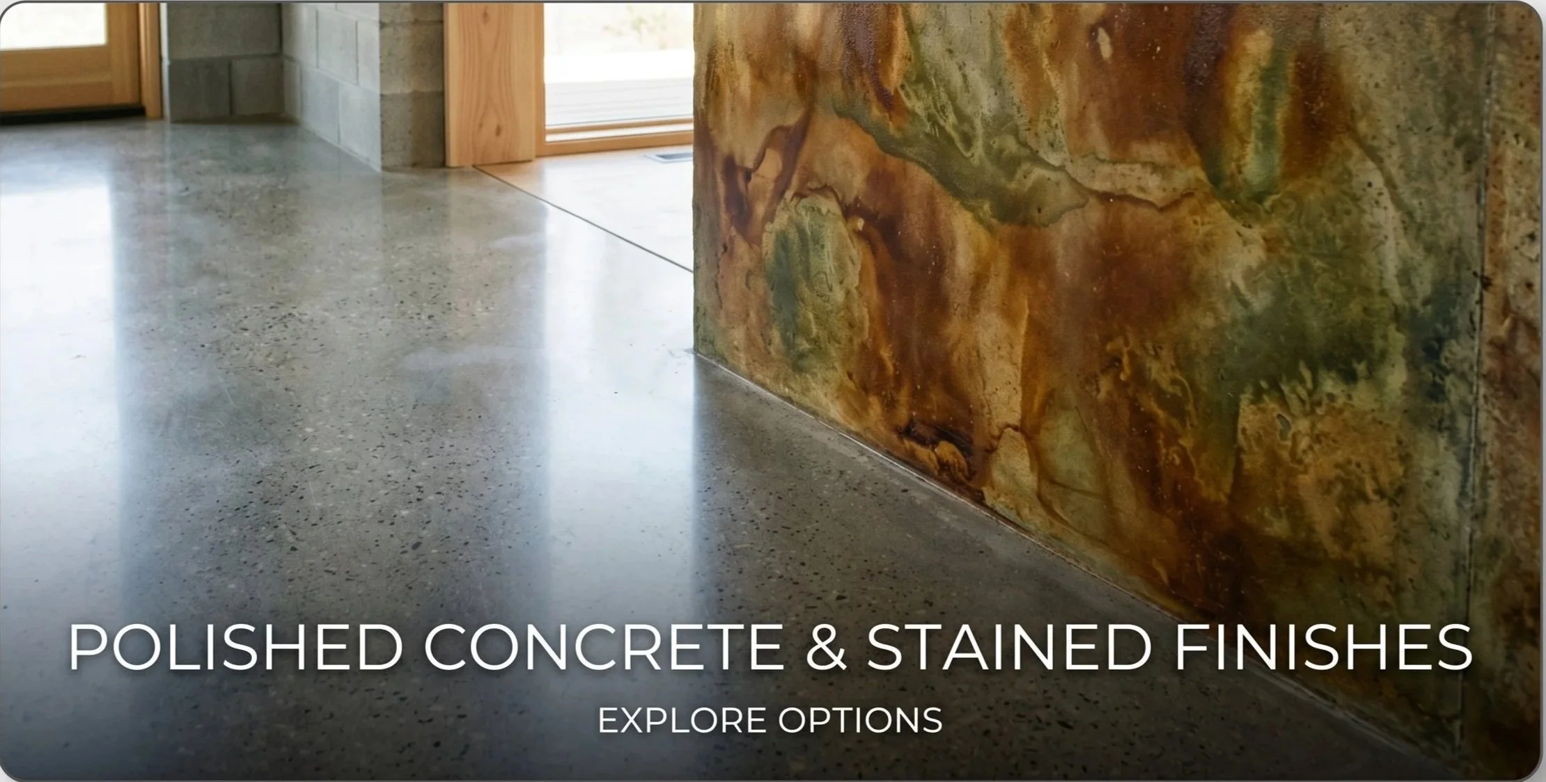 Close-up of polished concrete floor next to a stained, multicolored stone or tile wall in an interior space.