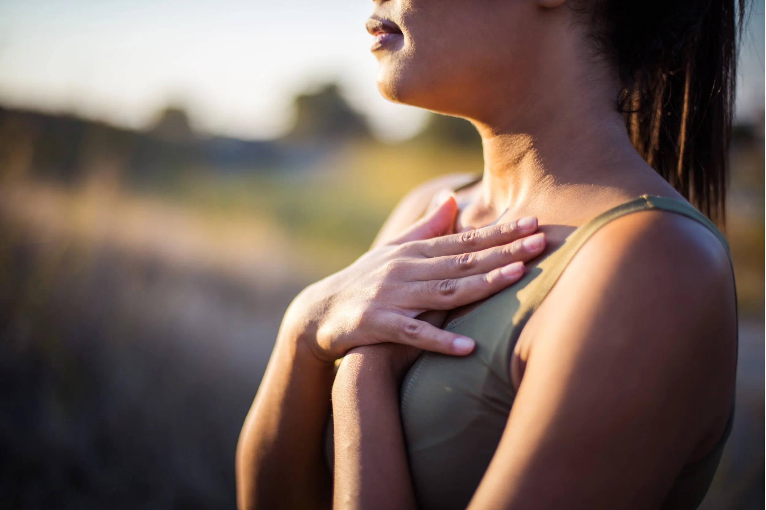 Woman with hands on chest outdoors