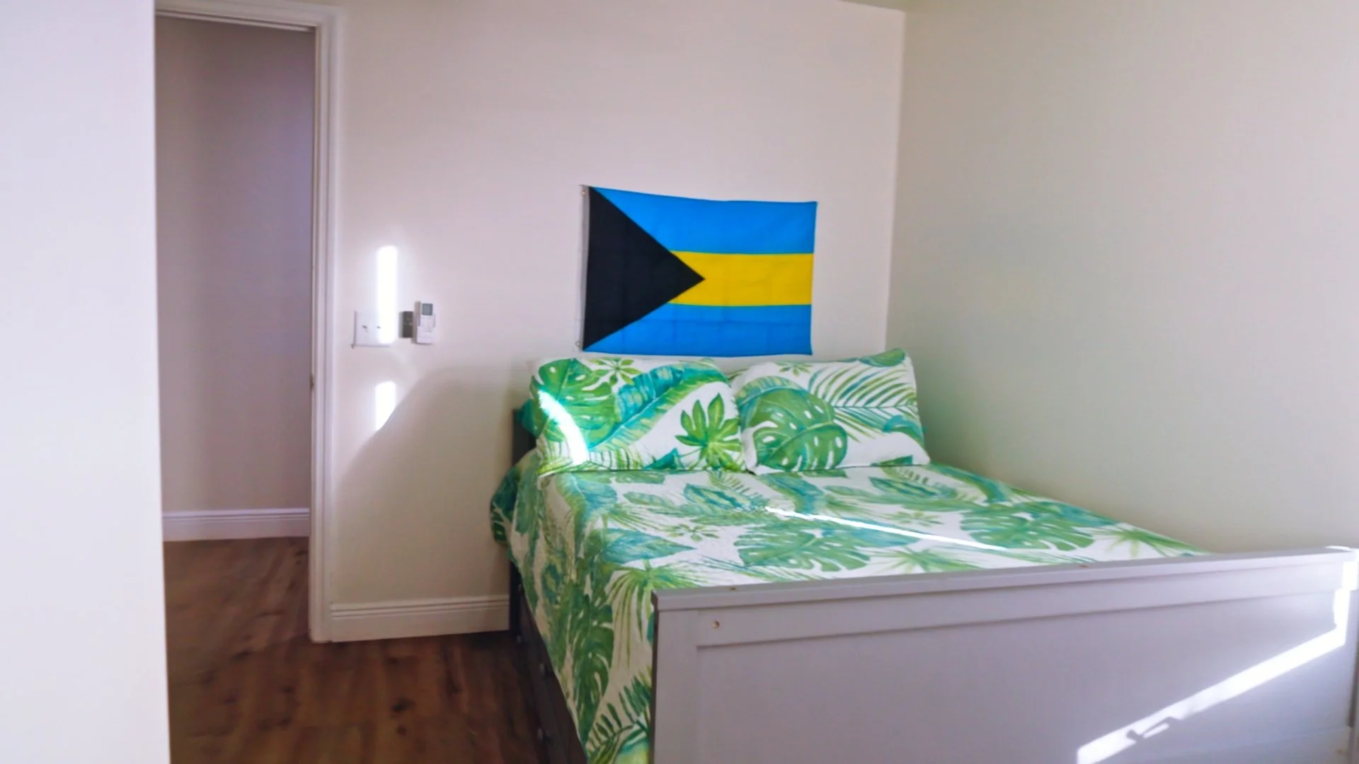 Tropical-style bedroom with Bahamas flag and green leaf bedding at B Happy vacation rental.
