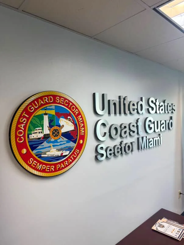 Conference room with a long wooden table and chairs, red brick wall with a fire department crest, whiteboard, and dim ceiling lights.