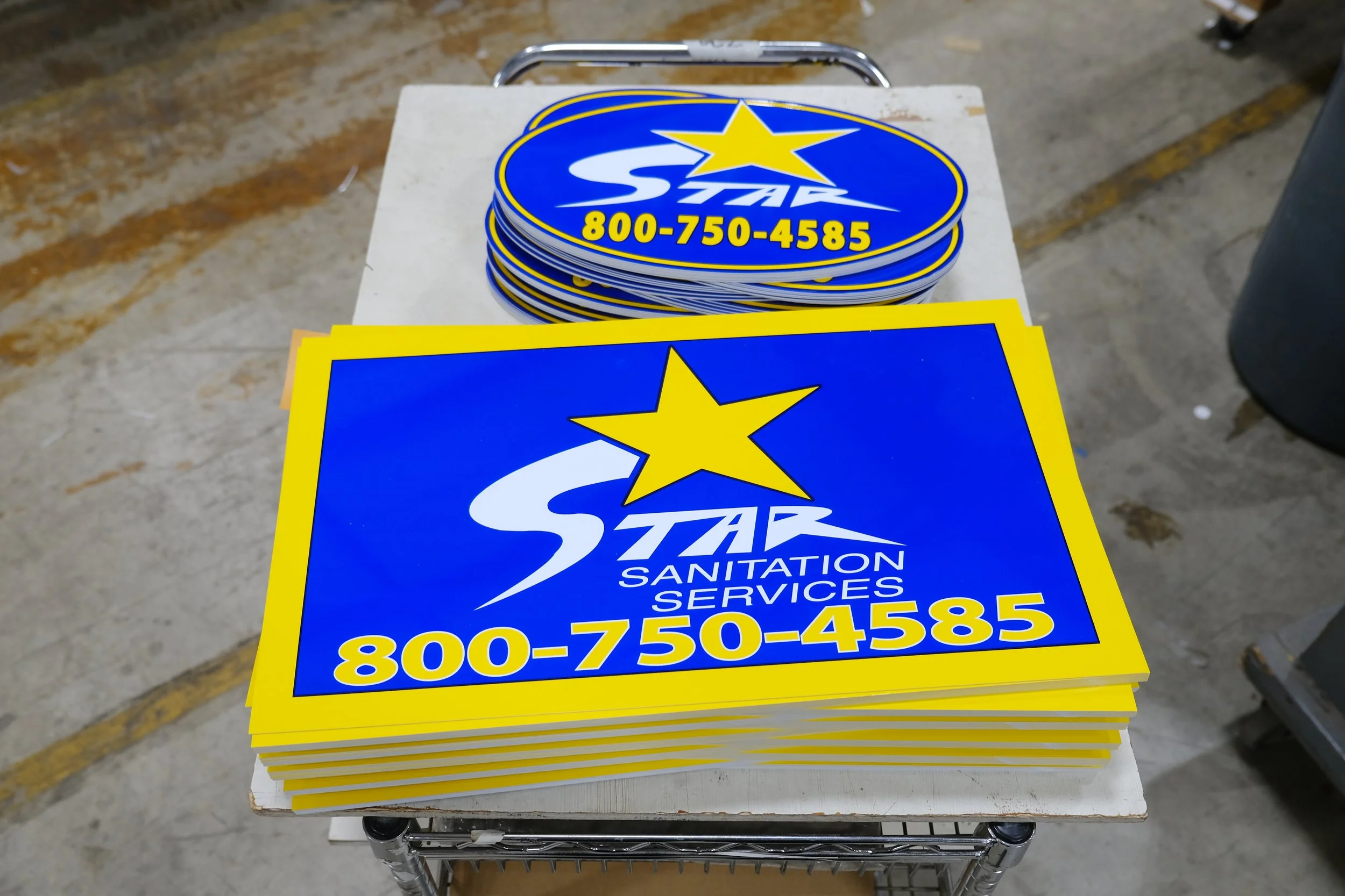 Close-up of a blue service vehicle with the logo of Service Sanitation, Inc., a phone number, and website printed on the side. The vehicle appears to be parked outdoors during sunset or sunrise.