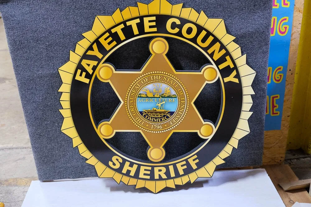 Fayette County Sheriff badge with a gold star and the county seal in the center.