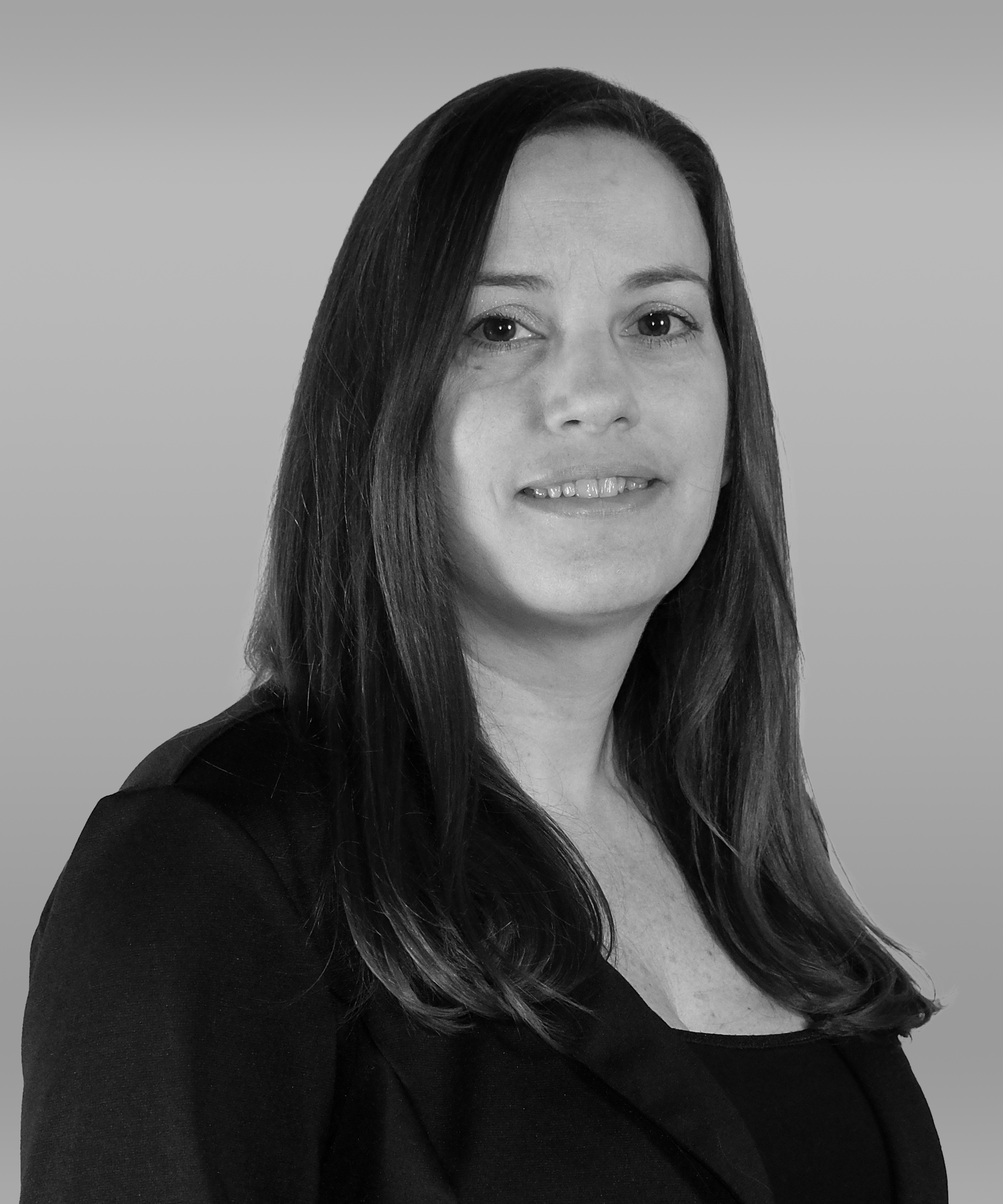Black and white portrait of a woman with long dark hair, wearing a black blazer, smiling softly, against a plain background.