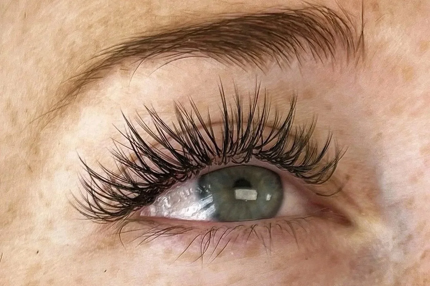 Close-up of a human eye with long, thick eyelashes and a blue iris.