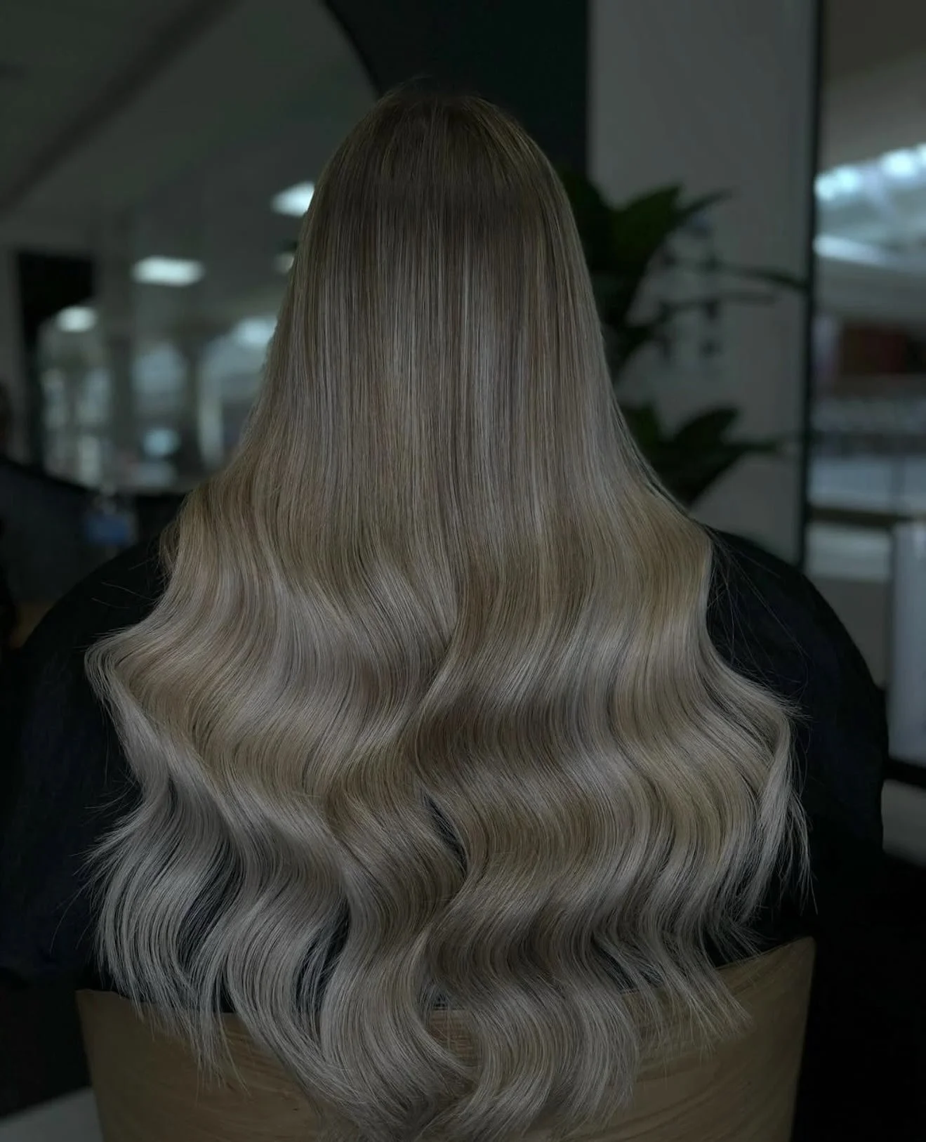 Back of a woman with long, wavy blonde hair.