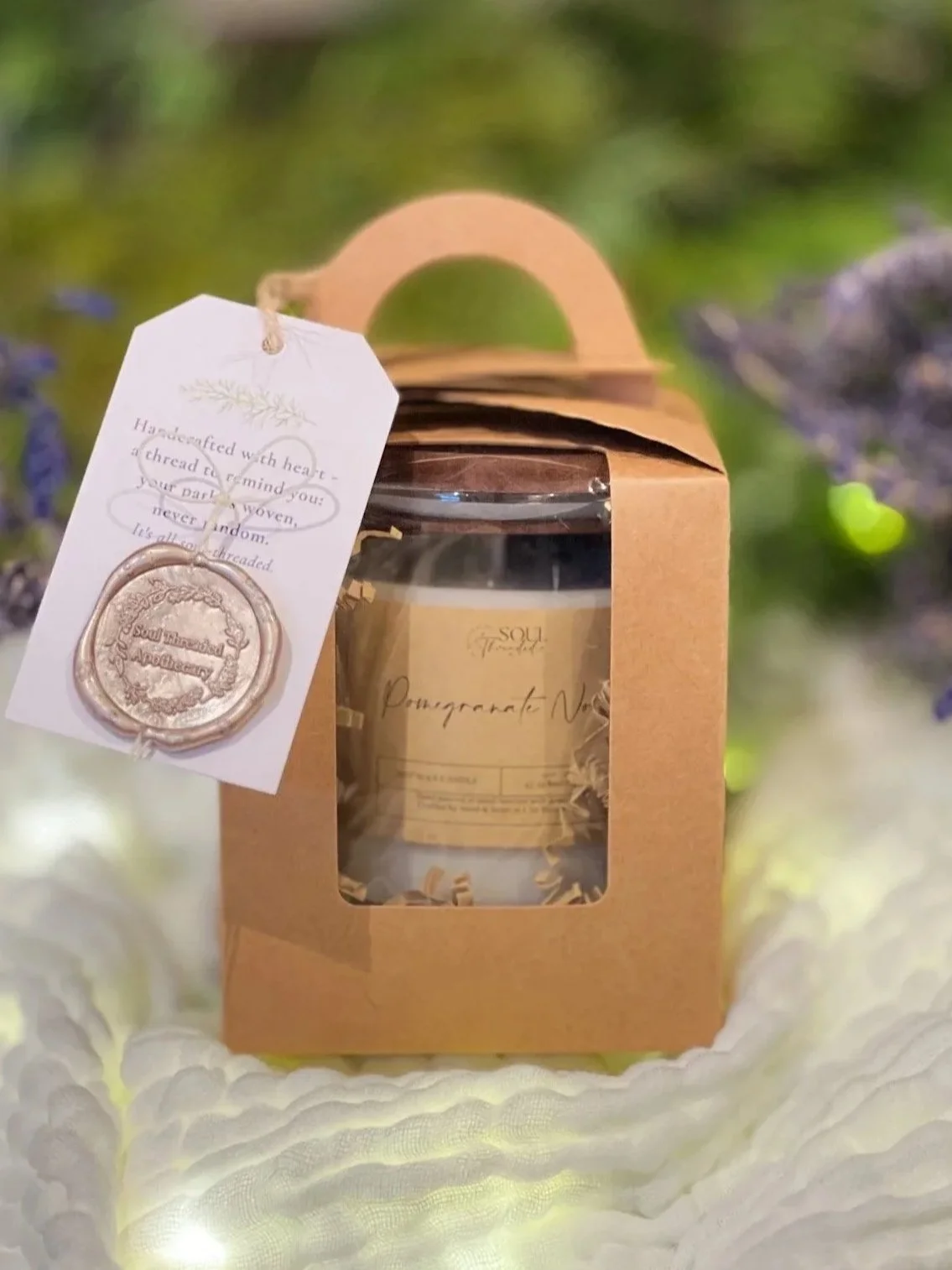 Soul Threaded 9oz hand-poured soy candle packaged in a Kraft gift box with dried botanicals, kraft crinkle and a wax-sealed tag.