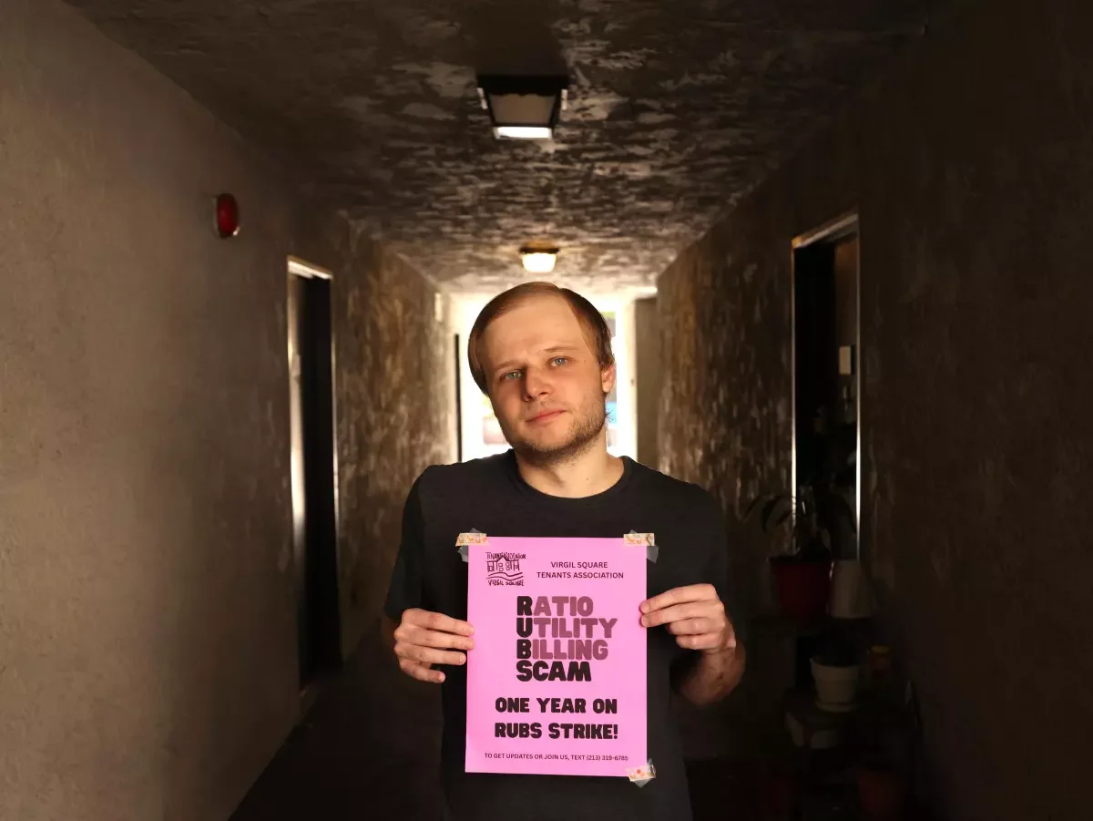 Tenant Joe Porter holding a "Ratio Utility Billing Scam" flyer.