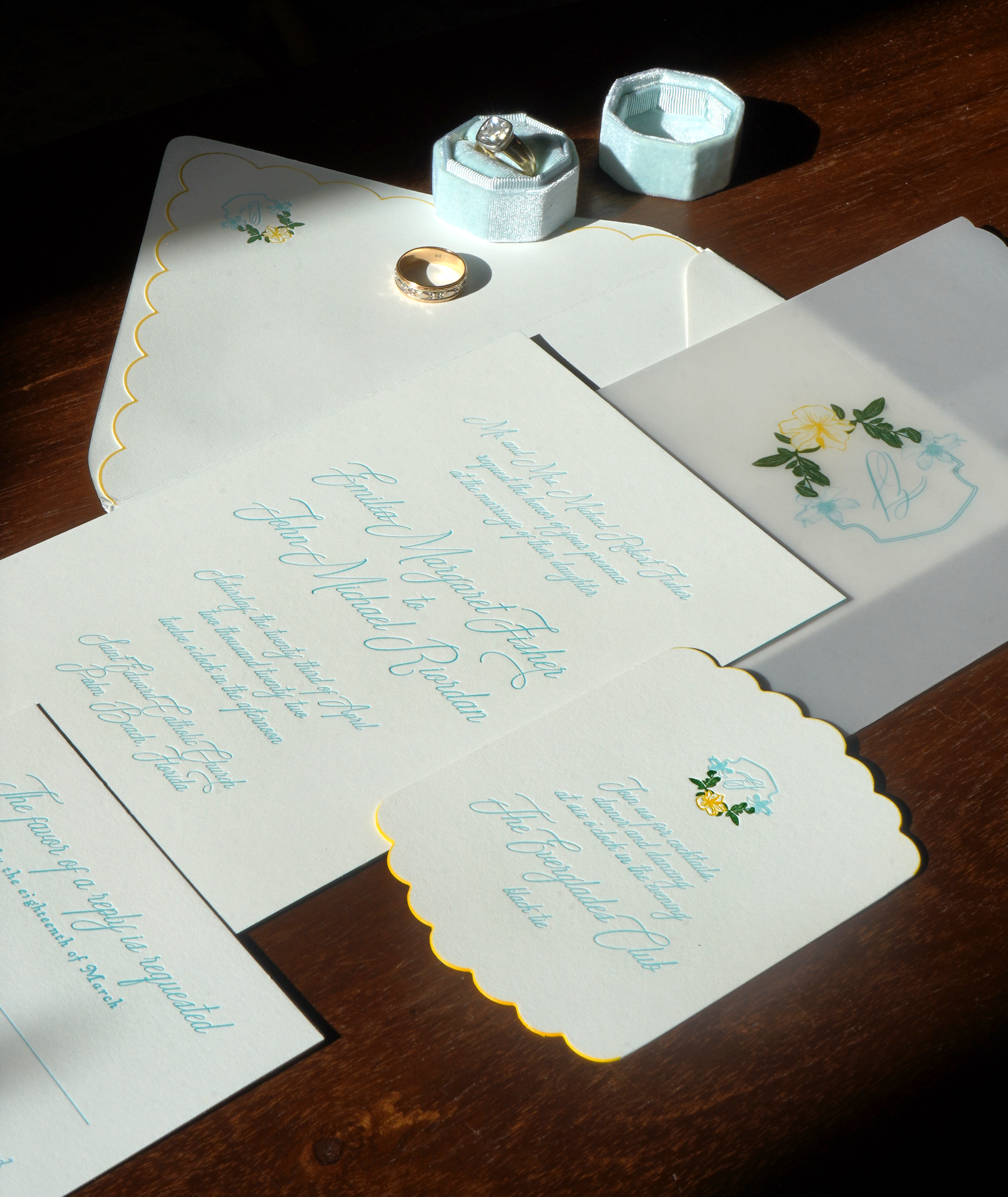 Bespoke wedding stationery with elegant blue calligraphy, custom envelopes, and refined details styled with wedding rings in an editorial flat lay