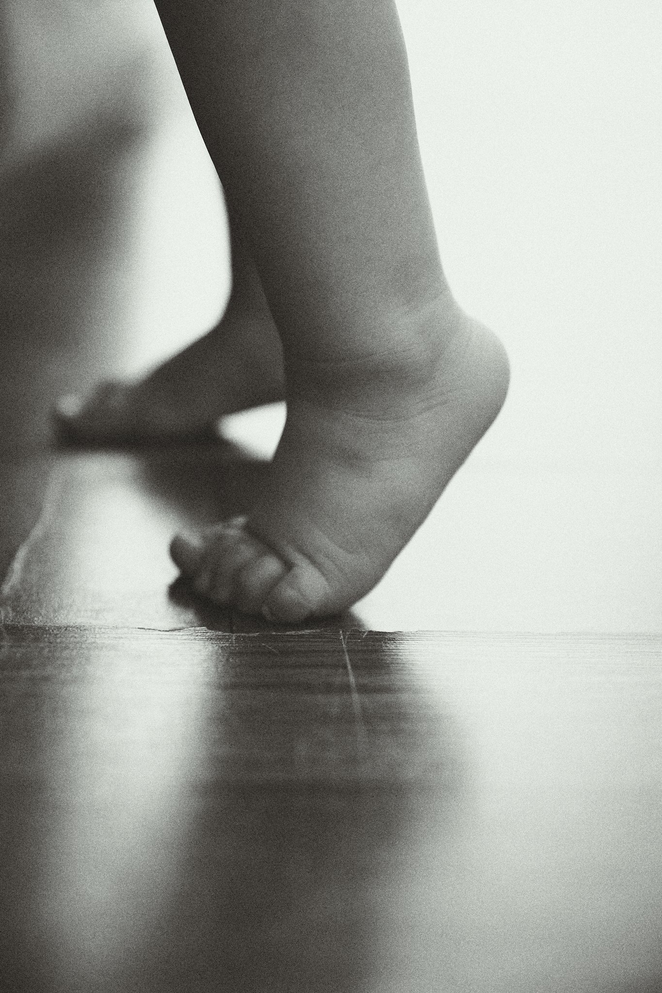 Close-up of a child's feet walking on a wooden floor.