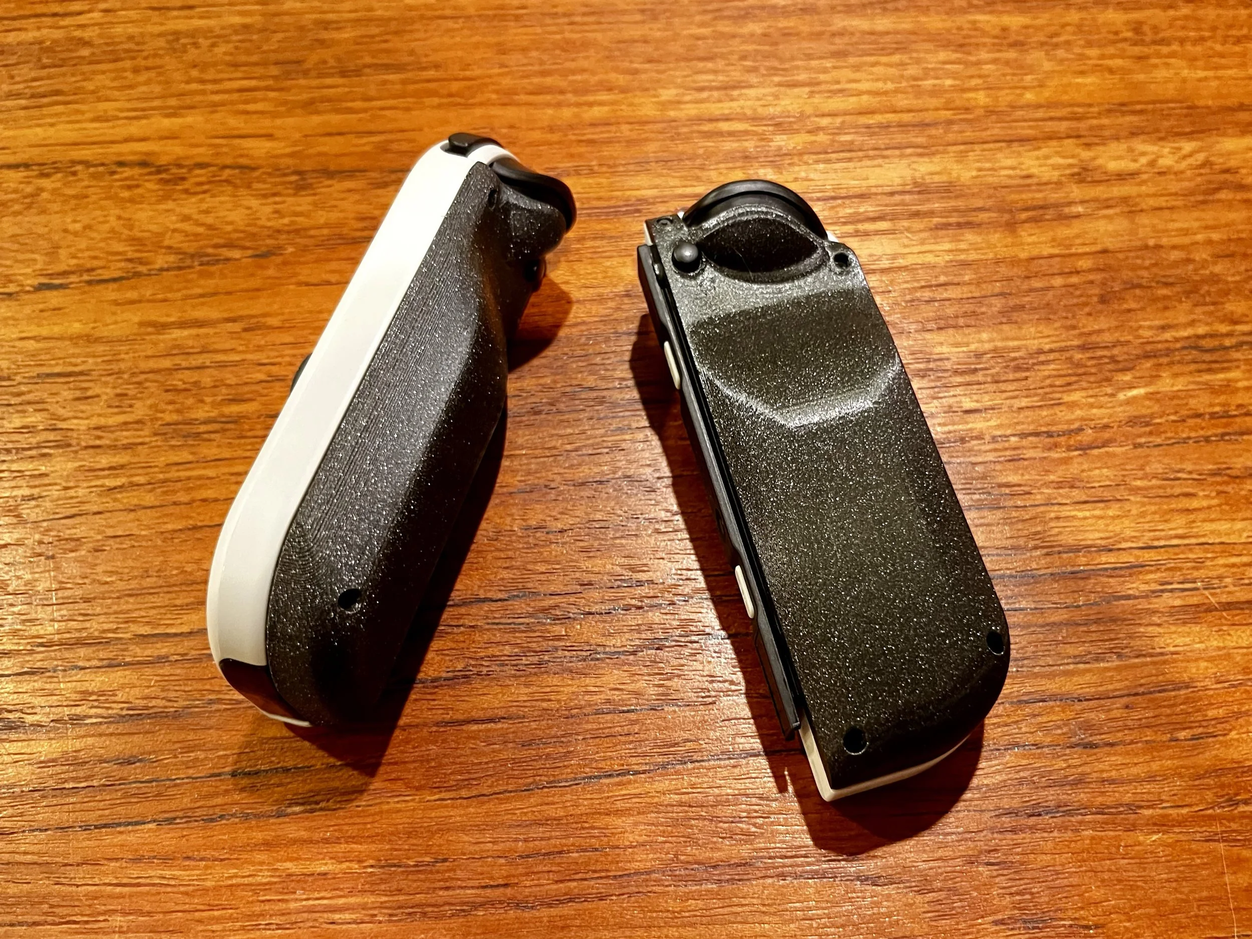 Two gaming controllers placed on a wooden surface.