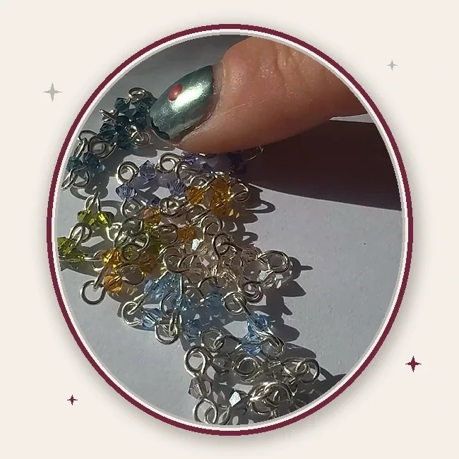 Hands move Vampire’s Kiss crystal rings through direct sunlight, making the beads and silver links flash inside an oval cameo frame.