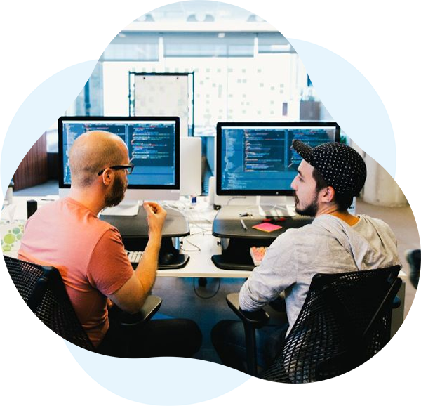Two men working on software development at desks with dual monitors in a modern office.
