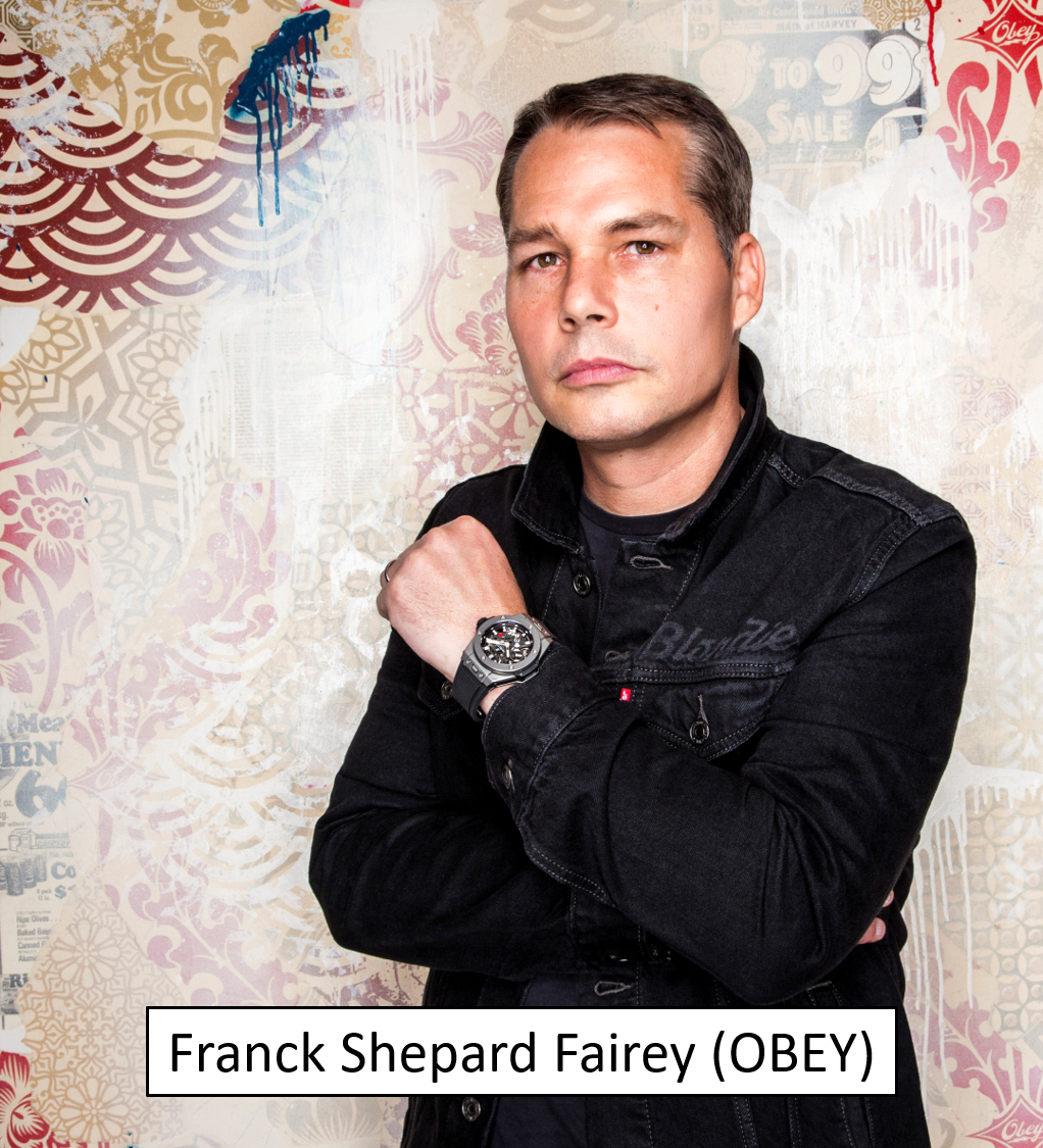 A man wearing a black denim jacket and a wristwatch, standing against a colorful, patterned wall background.