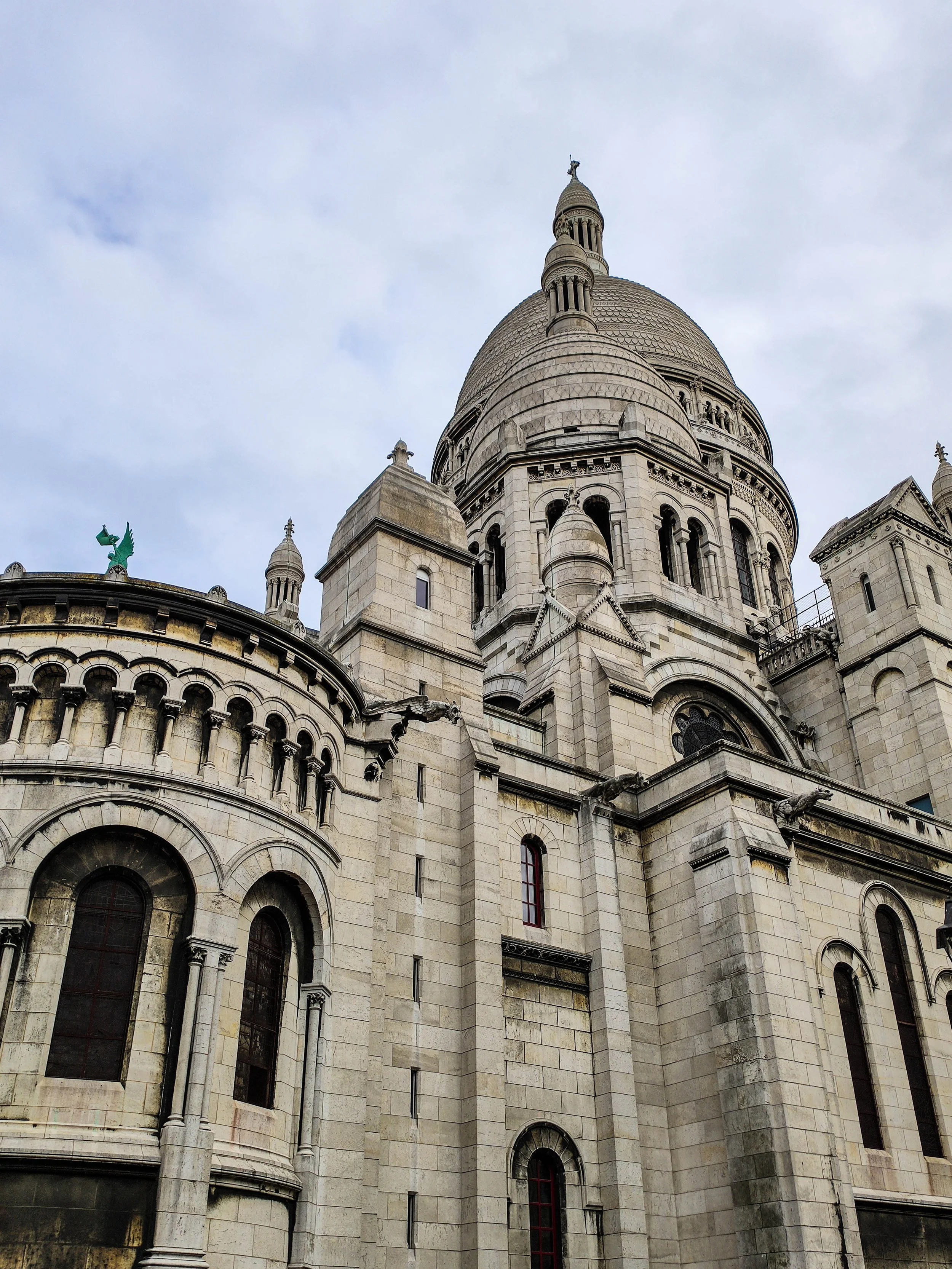 A large historic building with a prominent dome and ornate architecture, resembling a cathedral or basilica, under a cloudy sky.