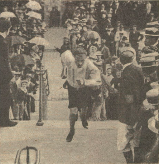 A vintage photograph of a man running up the stairs amid a crowd of spectators, with many wearing hats, in an outdoor setting.