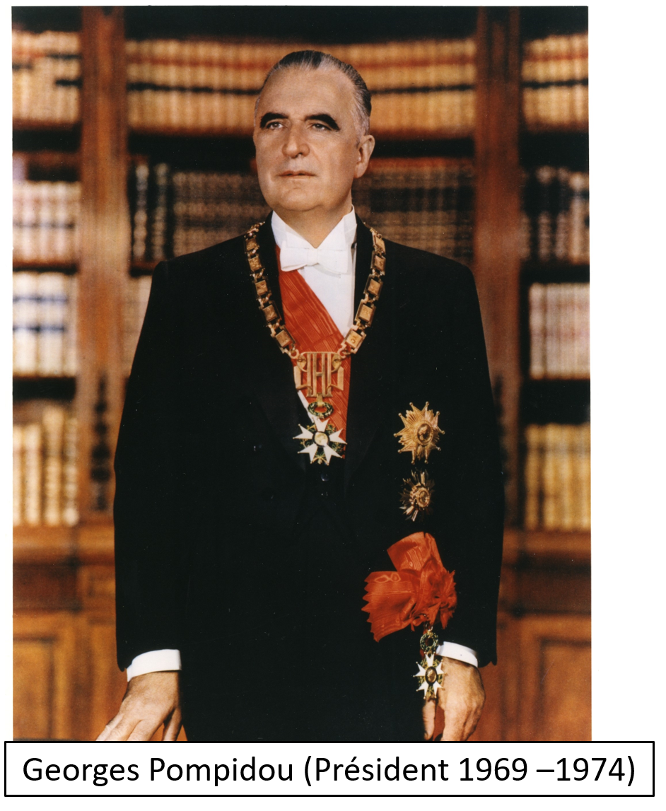 A man in formal attire with medals and decorations, standing in front of a background of bookshelves filled with books.