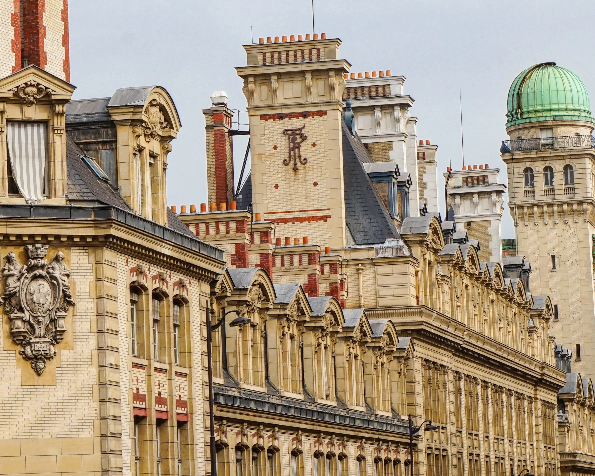 Historic European-style building with ornate architecture, decorative sculptures, and a green-domed tower.