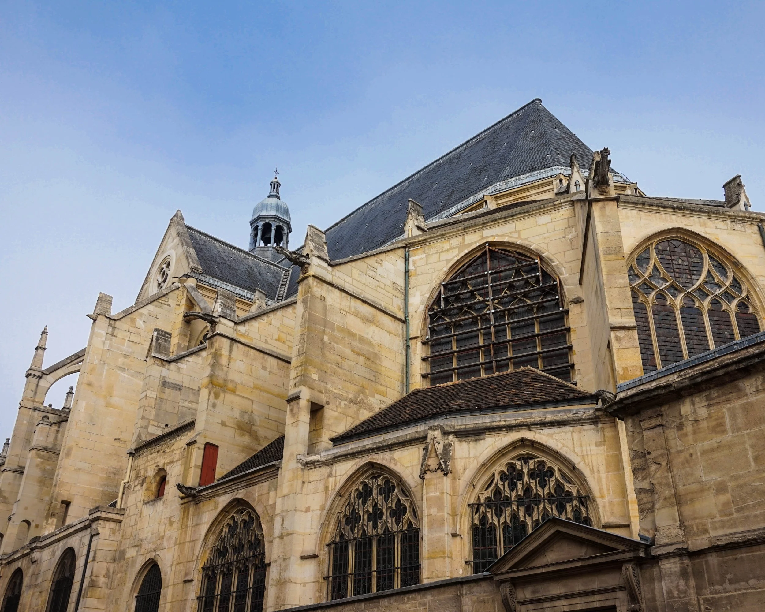 Close-up view of an old stone church with large stained glass windows and gothic architectural details, under a clear sky.