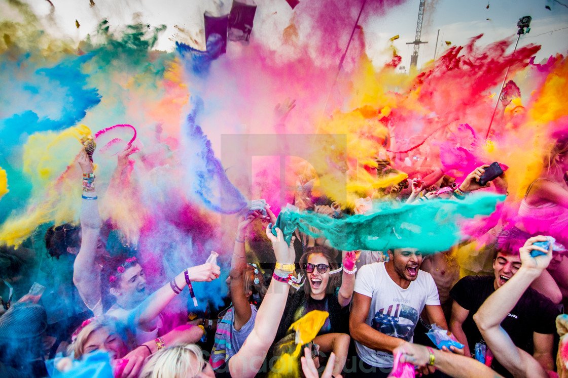 People celebrating at a color festival throwing colorful powder into the air.