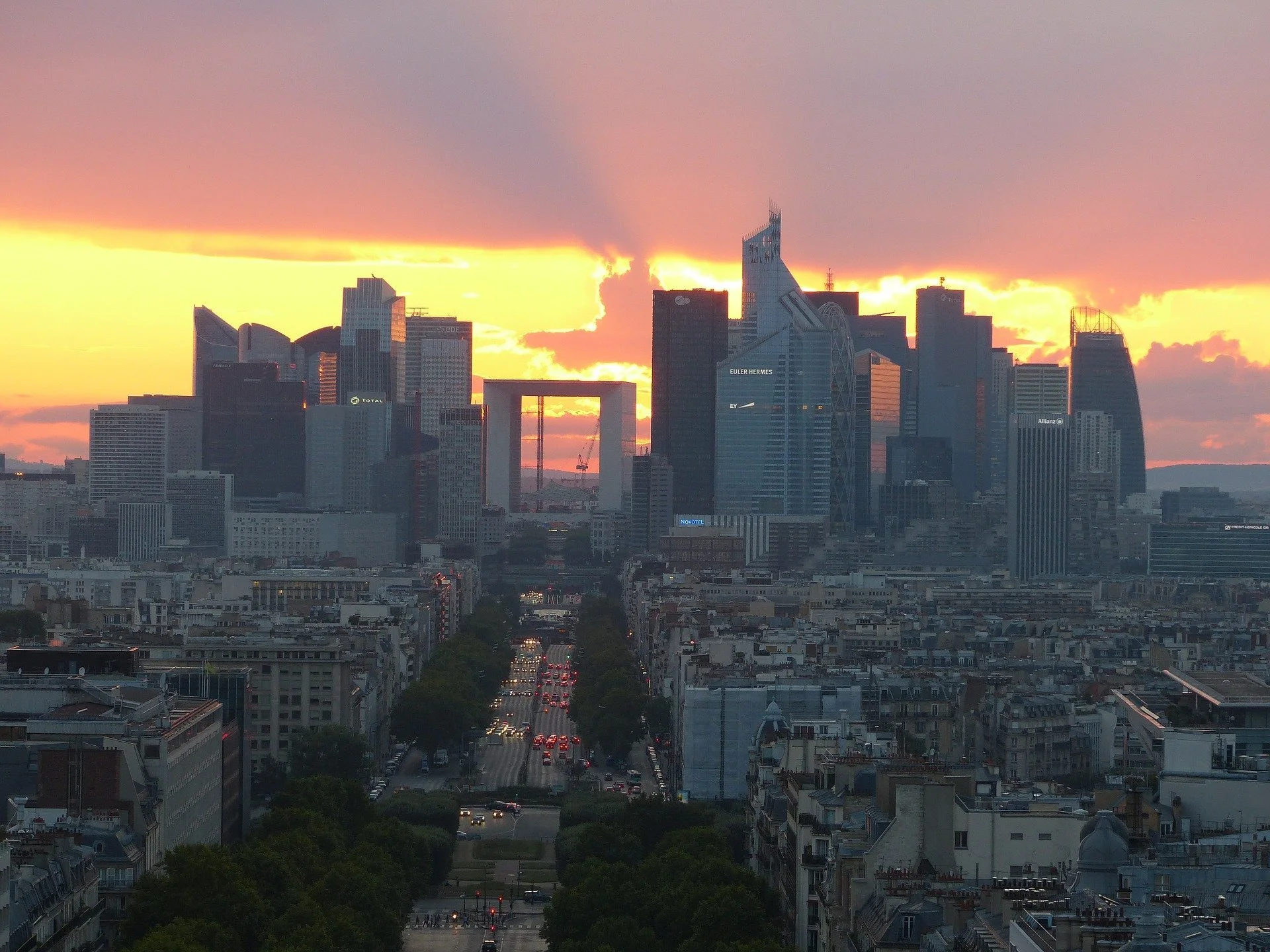 City skyline during sunset with tall modern buildings and a cloudy sky.