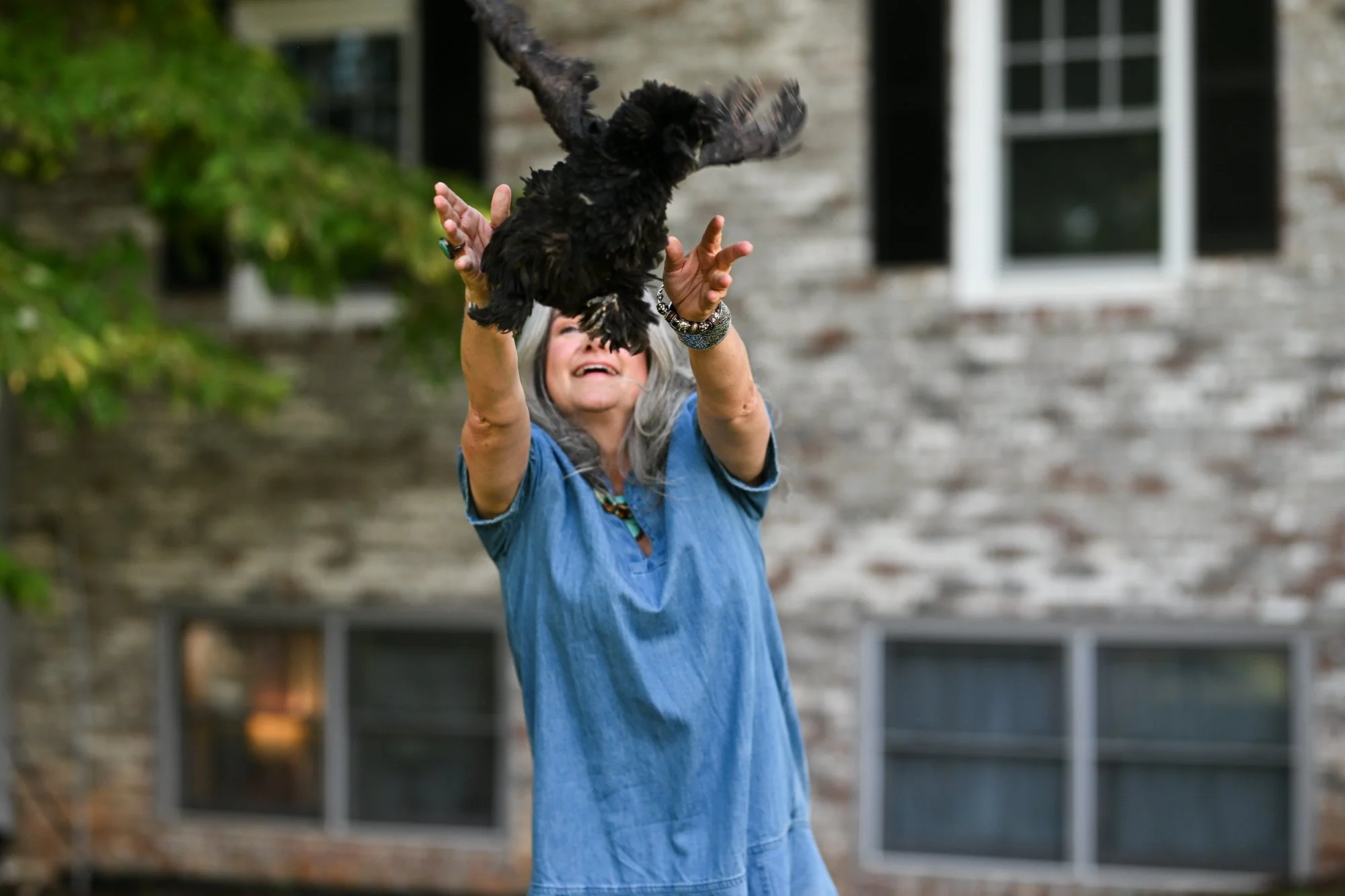 Morgan Brawley, LCMHCA, laughing as she releases a black chicken into the air