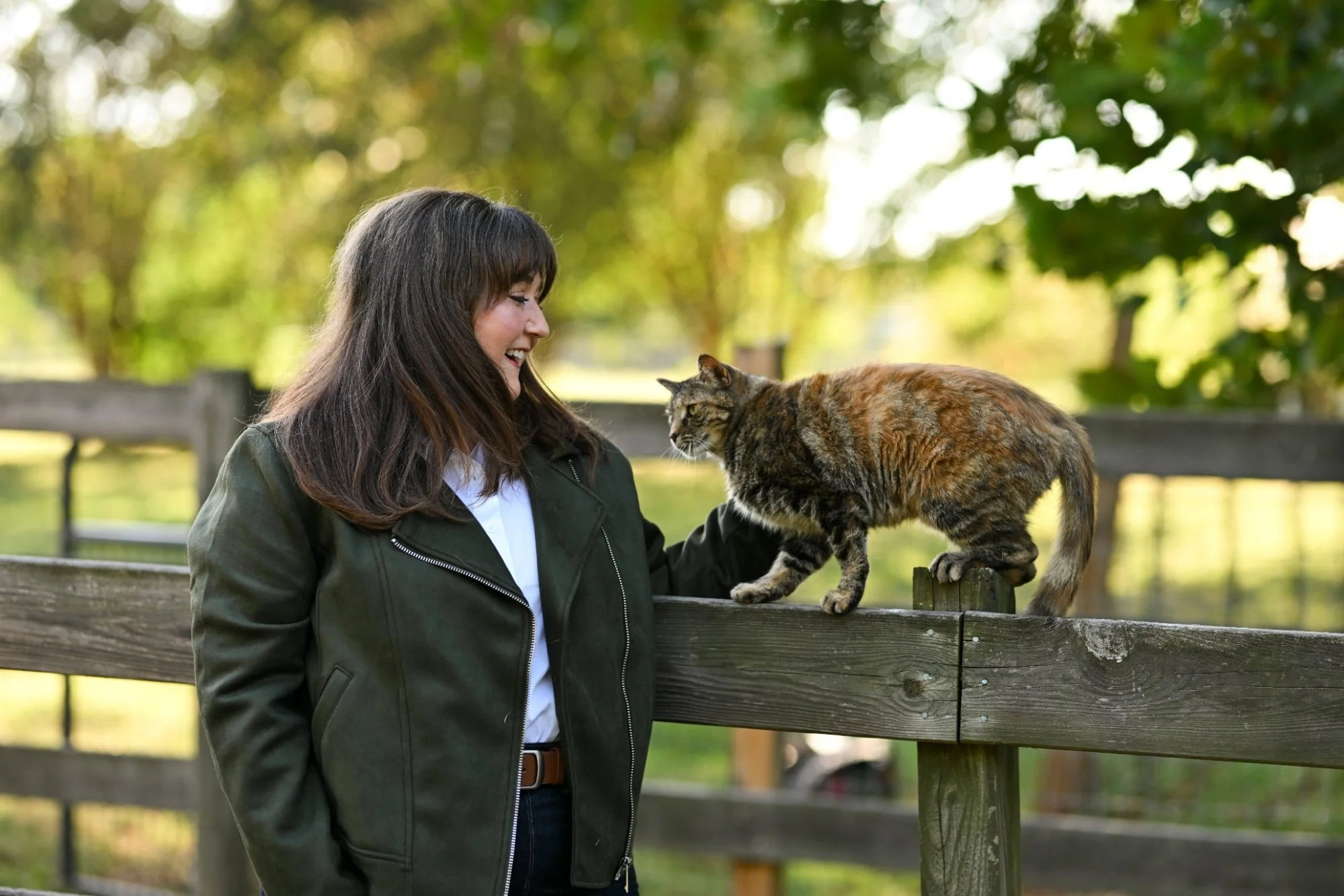 Jordan Peterson, LCMHCA, smiling at a tortoiseshell barn cat on a wooden fence