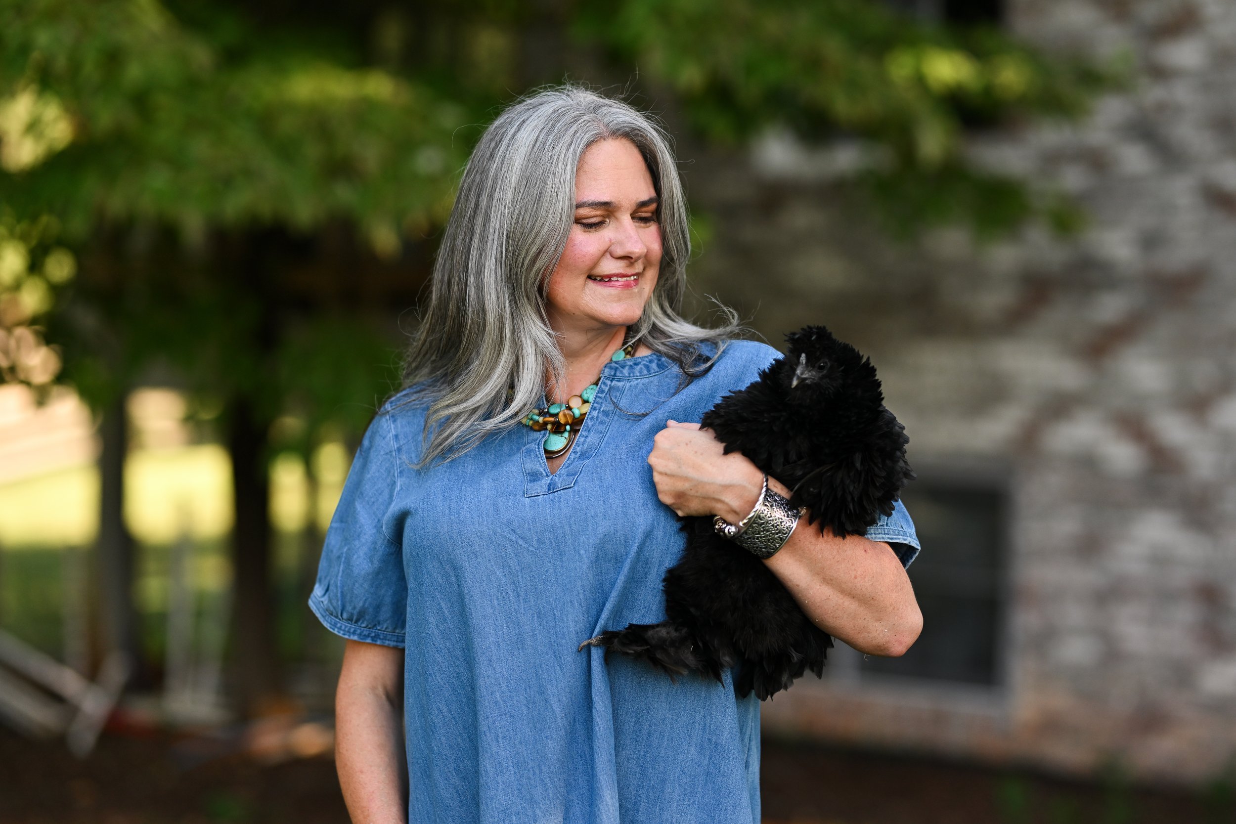 Morgan Brawley, LCMHCA, smiling as she holds a black chicken
