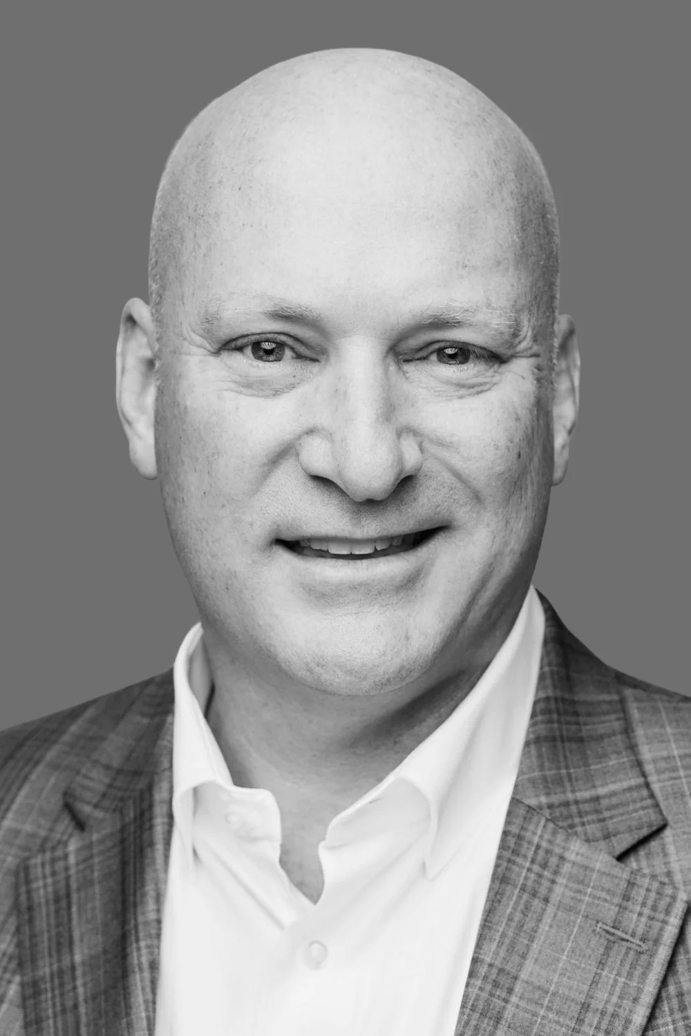 Black and white headshot of a middle-aged man wearing a suit, and smiling at the camera.