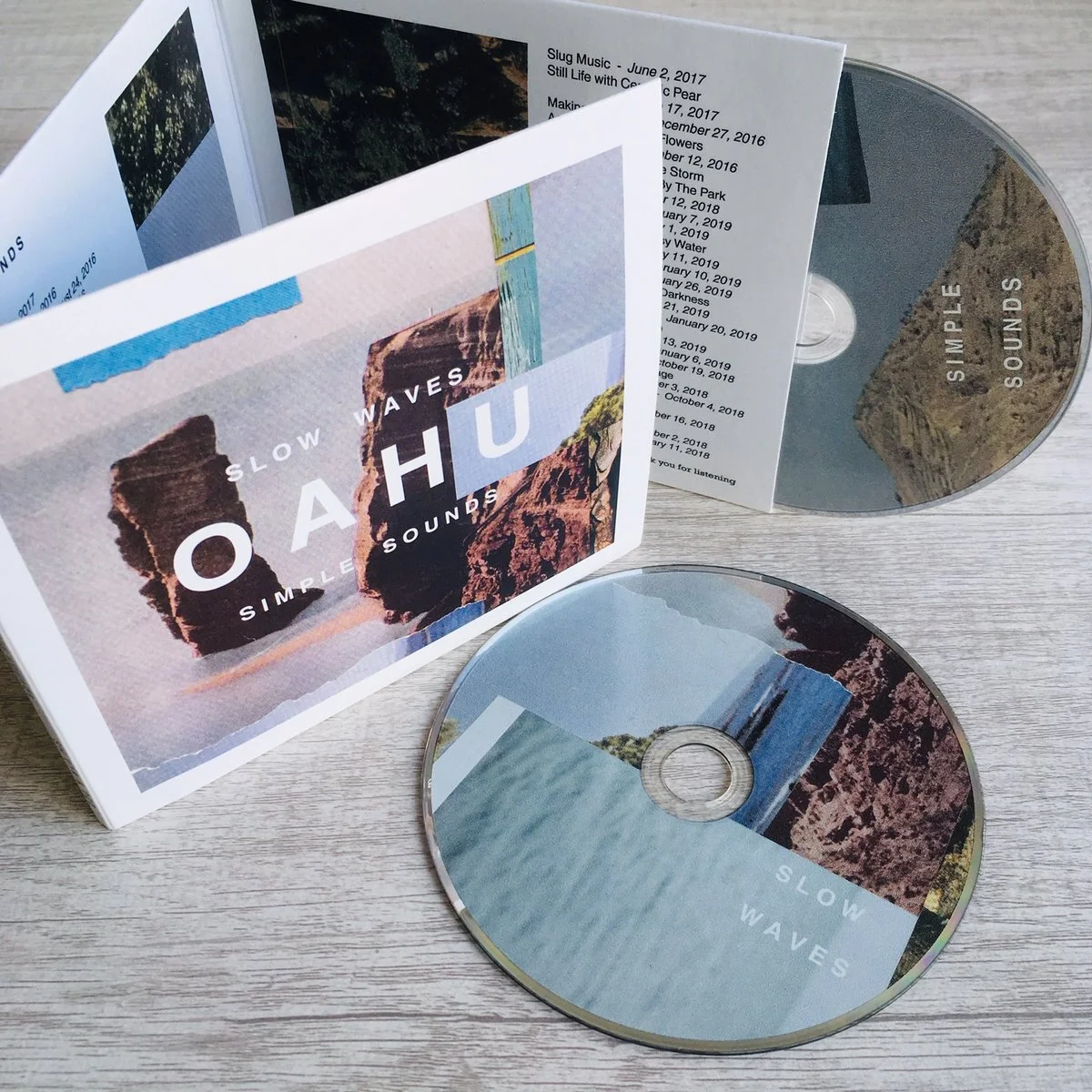 Open box set of CDs titled 'Slow Waves' by 'Oahu' with cover art featuring coastal cliffs and water, and included booklet with tracklist.