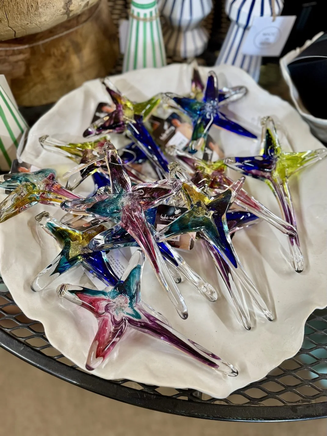 Colorful glass star-shaped ornaments displayed on a white cloth in a store.