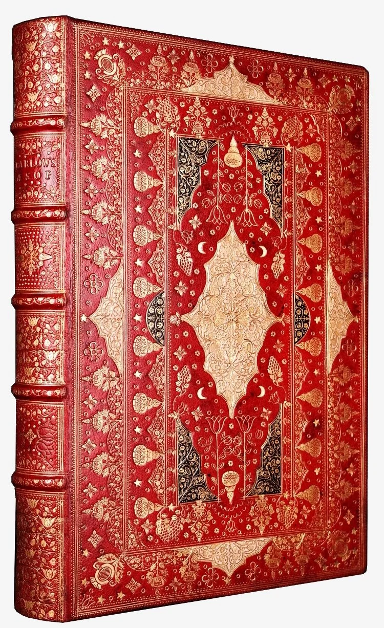 A red and gold ornate rare book with intricate gold tooling and leatherwork.