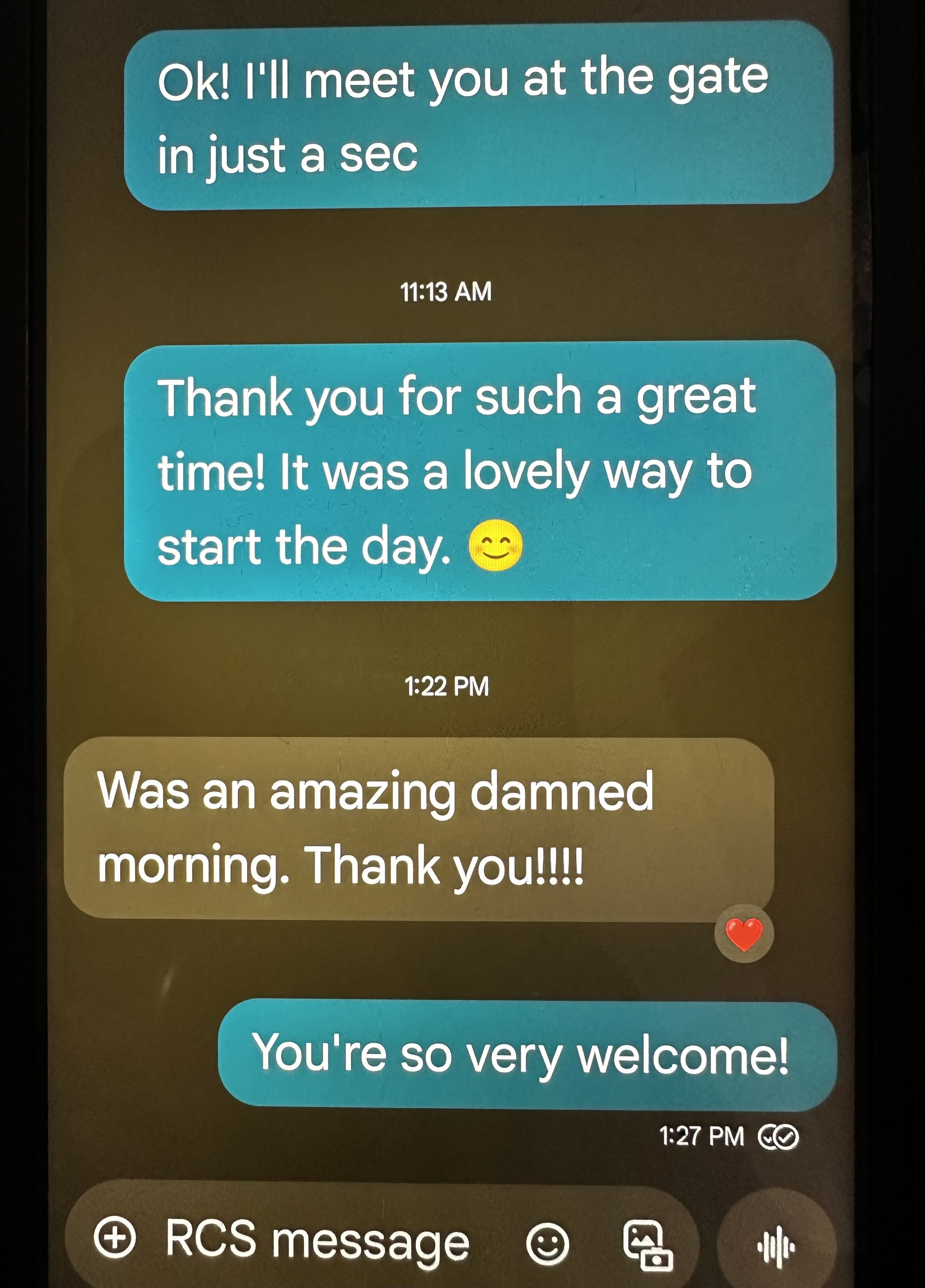 Screenshots of a text message conversation showing a friendly exchange, with teal and beige message bubbles, timestamps, emojis including a smiling face and a heart, and icons for messaging options at the bottom.