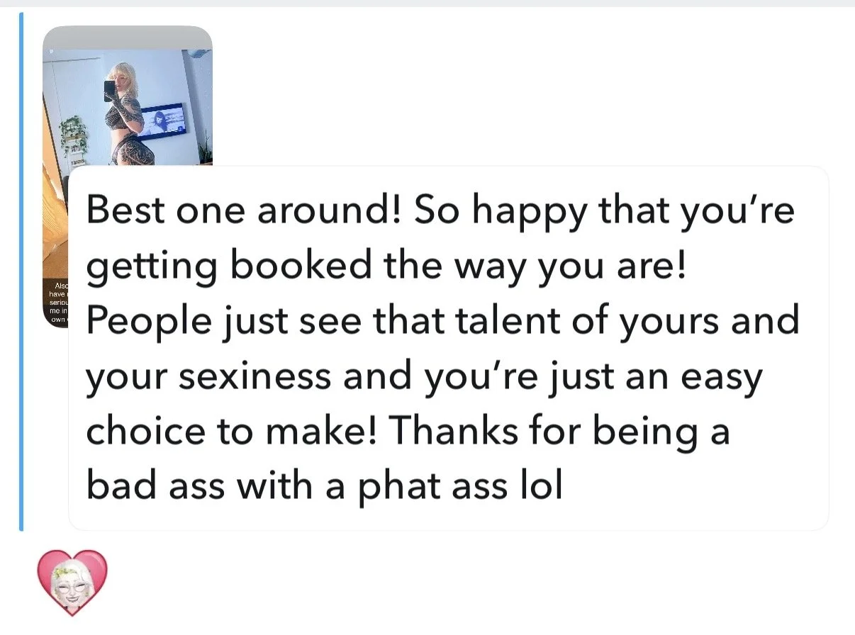 A woman taking a mirror selfie, wearing black and white patterned clothing and glasses.