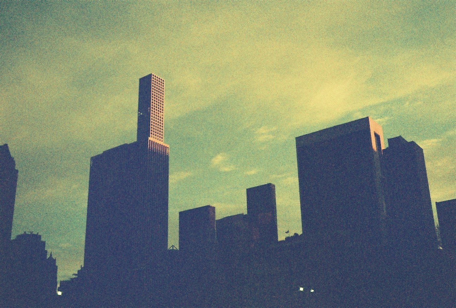 Silhouette of city skyline with skyscrapers at dusk, featuring a prominent tall building.