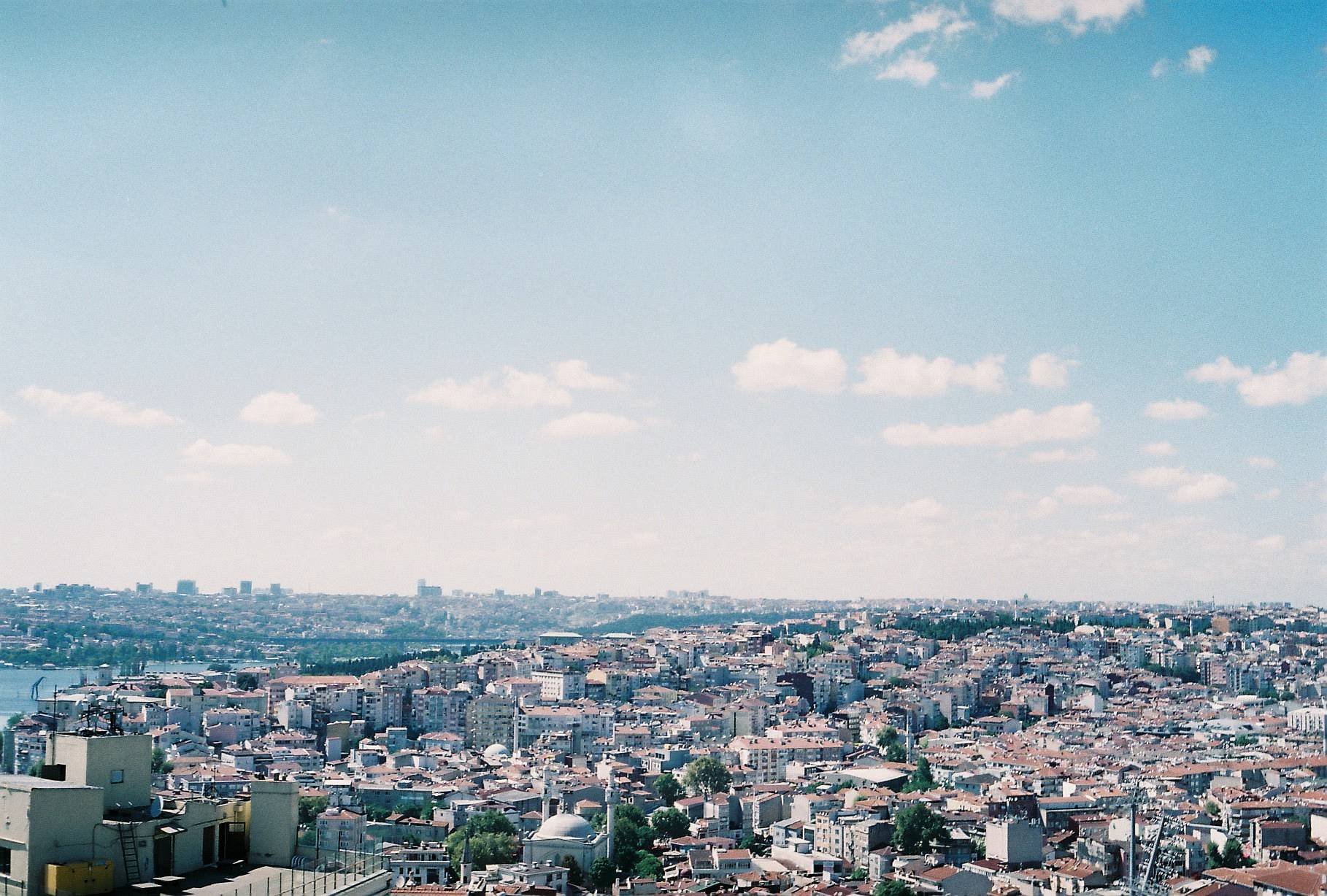Panoramic view of a cityscape with densely packed buildings under a blue sky with scattered clouds.