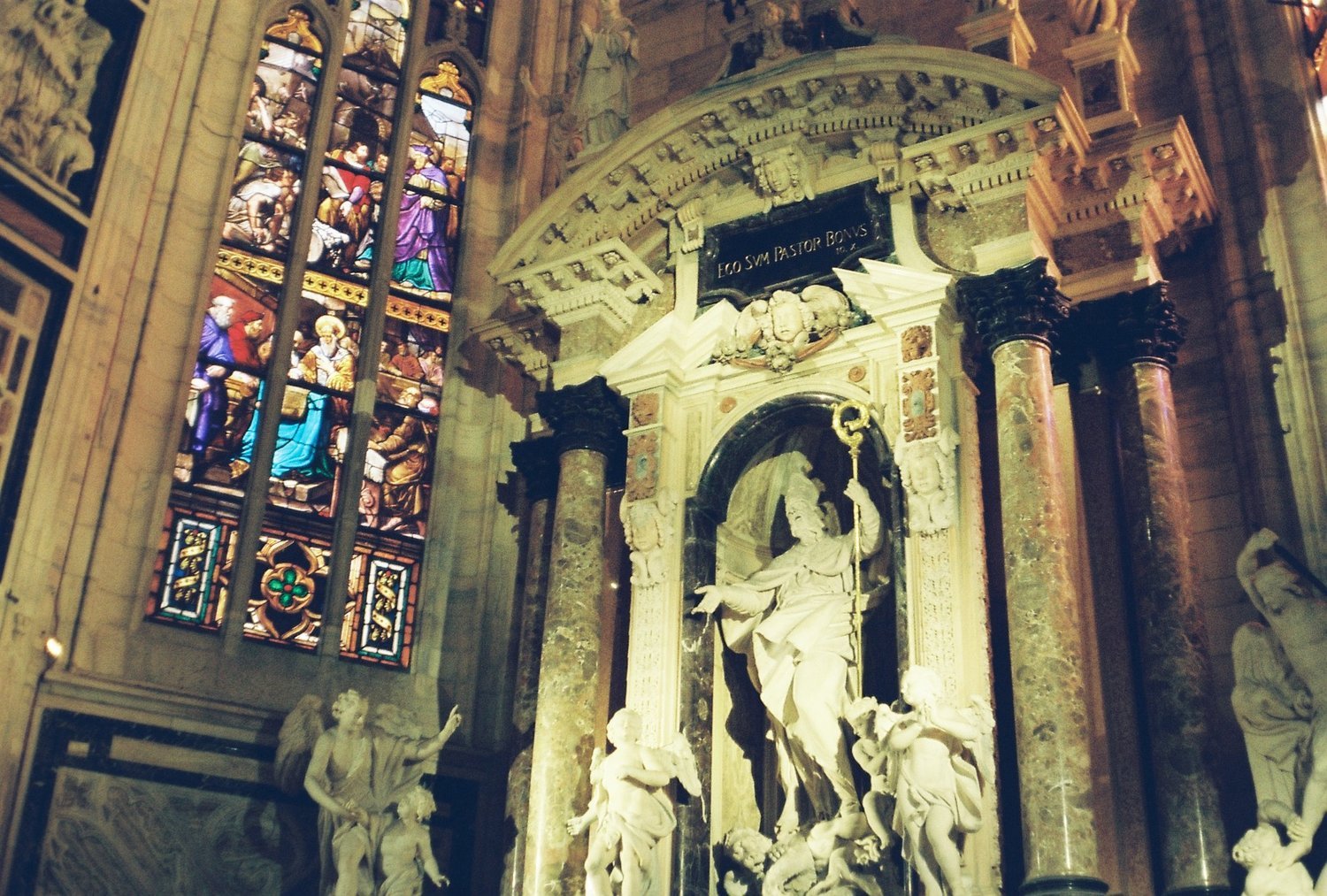 Interior of a cathedral with stained glass windows and marble sculptures