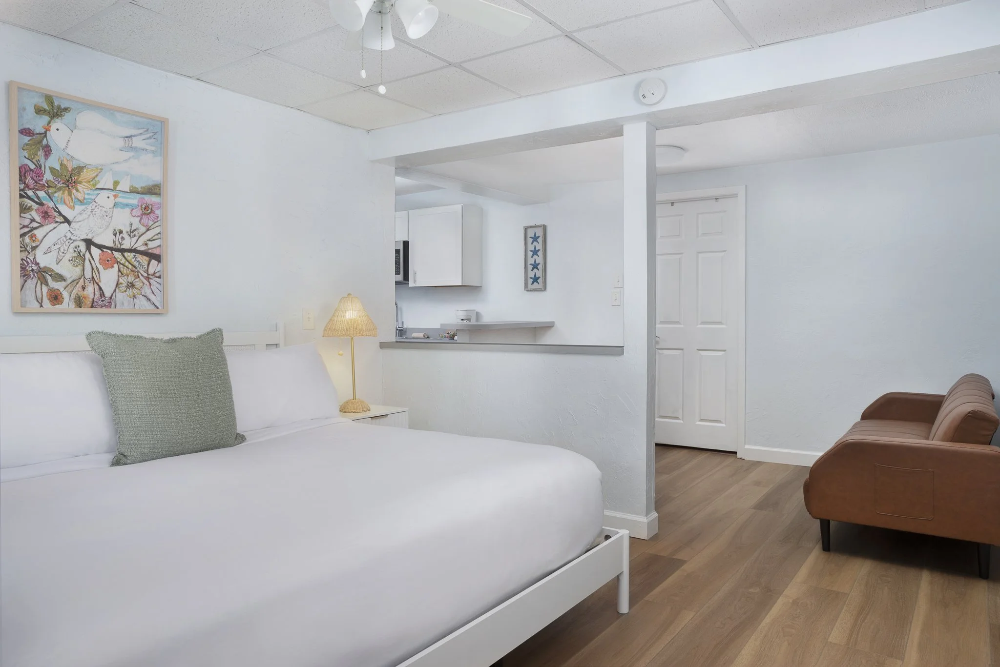Cozy boutique hotel suite with modern leather sofa, beach-themed decor, and natural light at Sabal Palms Inn near St. Pete Beach
