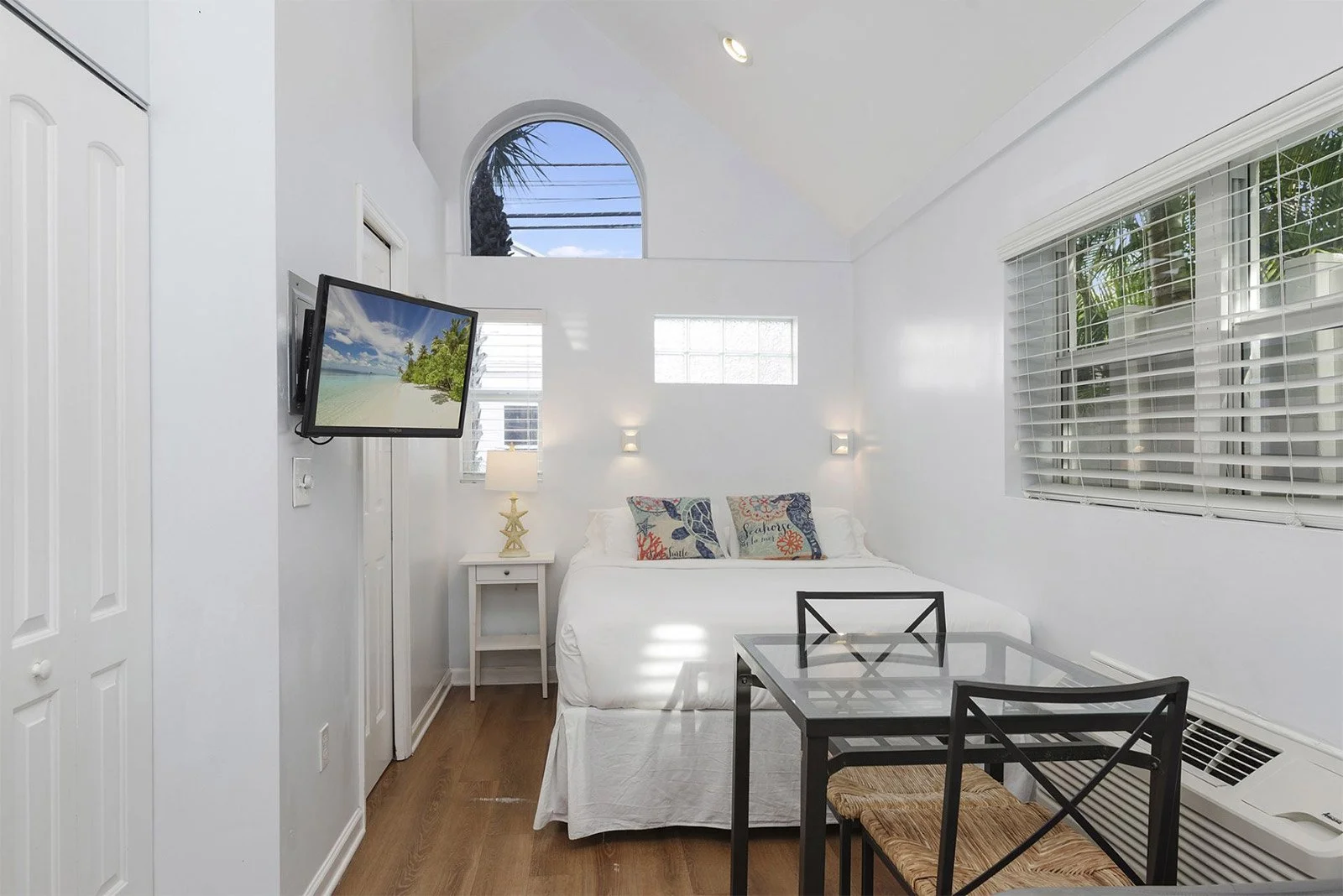 Cozy suite at Havana Inn, a boutique hotel in Pass-a-Grille, featuring a queen bed, dining area, flat-screen TV, and beach-inspired decor