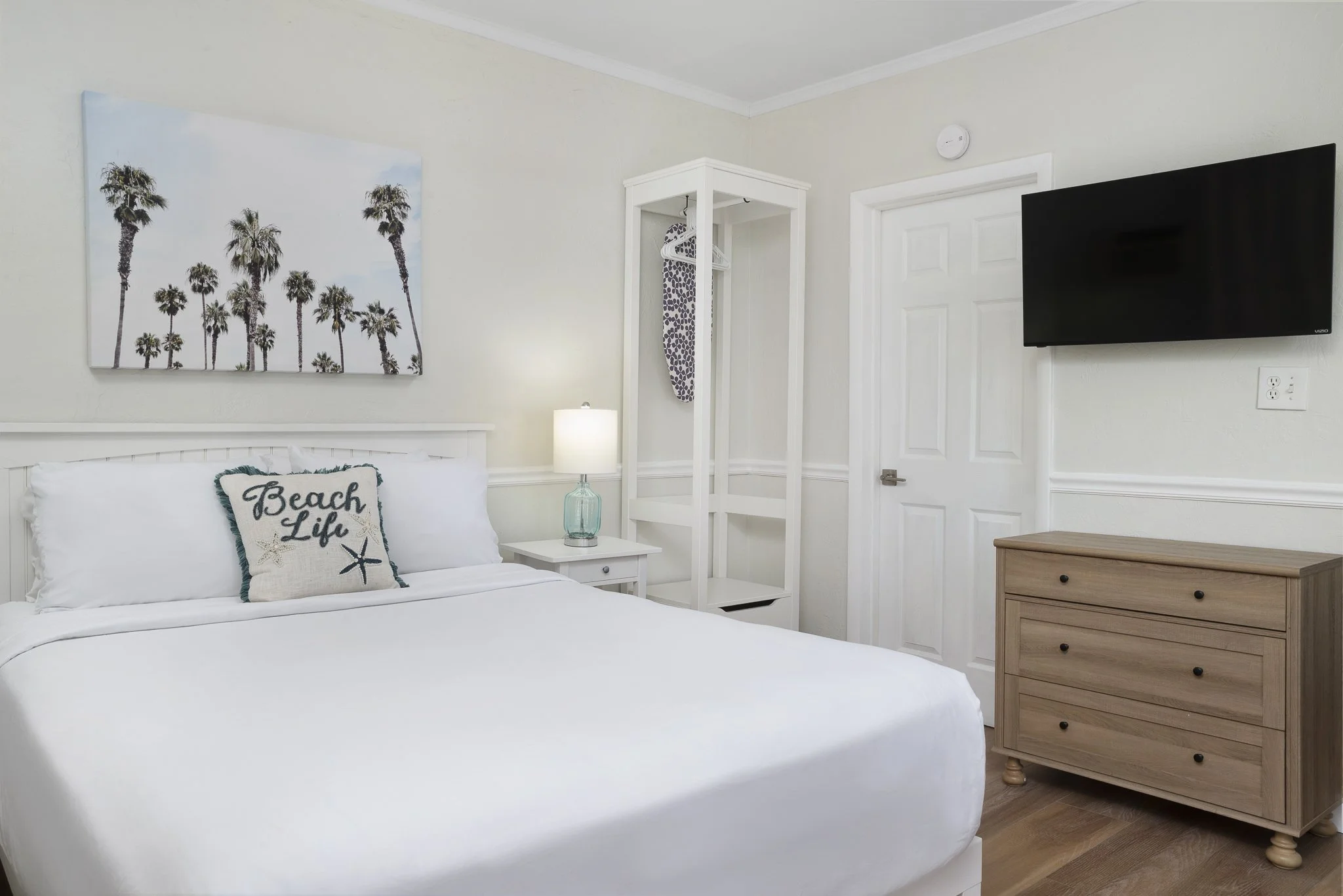 Bright beachside boutique hotel suite featuring a queen bed, coastal decor, and fully equipped kitchenette at Sabal Palms Inn near St. Pete Beach.