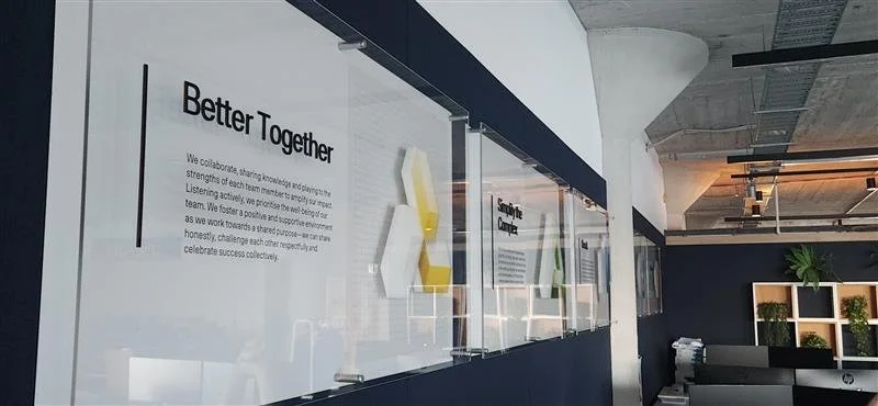 Office interior with a wall display titled 'Better Together' and decorative 3D geometric shapes