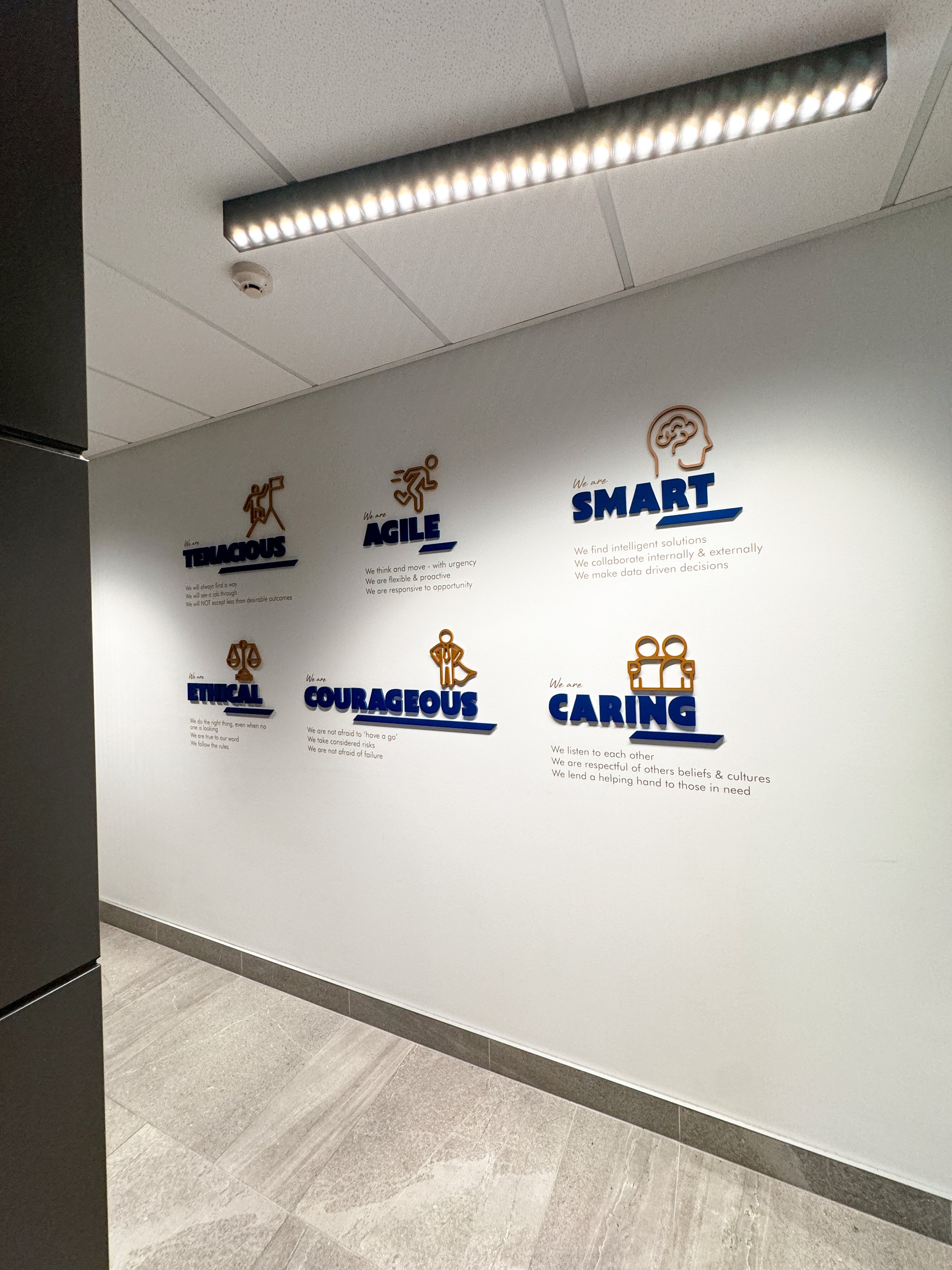 Wall decor detailing core values: diligent, agile, smart, ethical, courageous, and caring, with respective icons and descriptions.