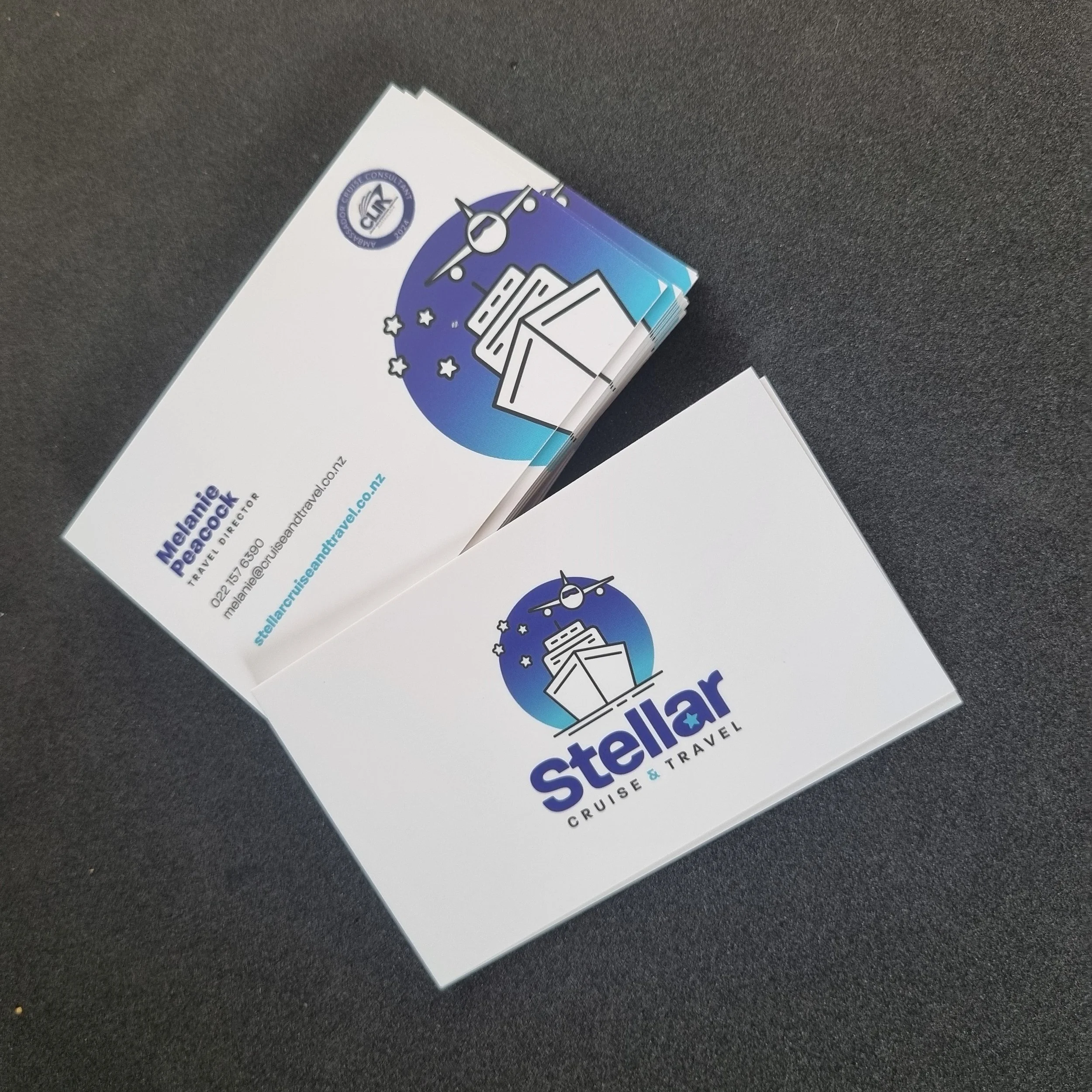 Business cards for Stellar Cruise & Travel, featuring a logo with an airplane and cruise ship against a blue circle background.