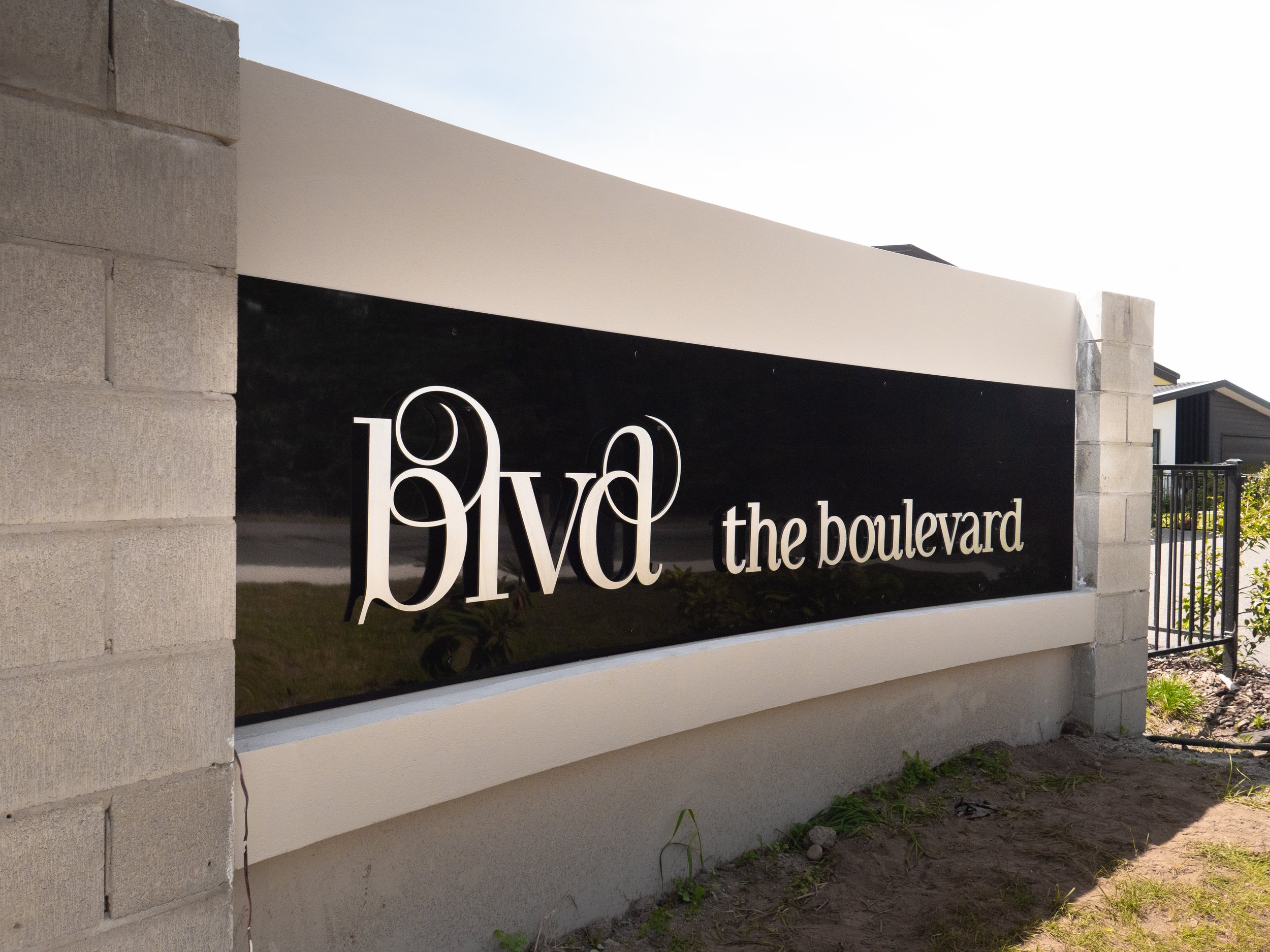 Sign for BVD The Boulevard with white letters on a black background, attached to a beige wall.