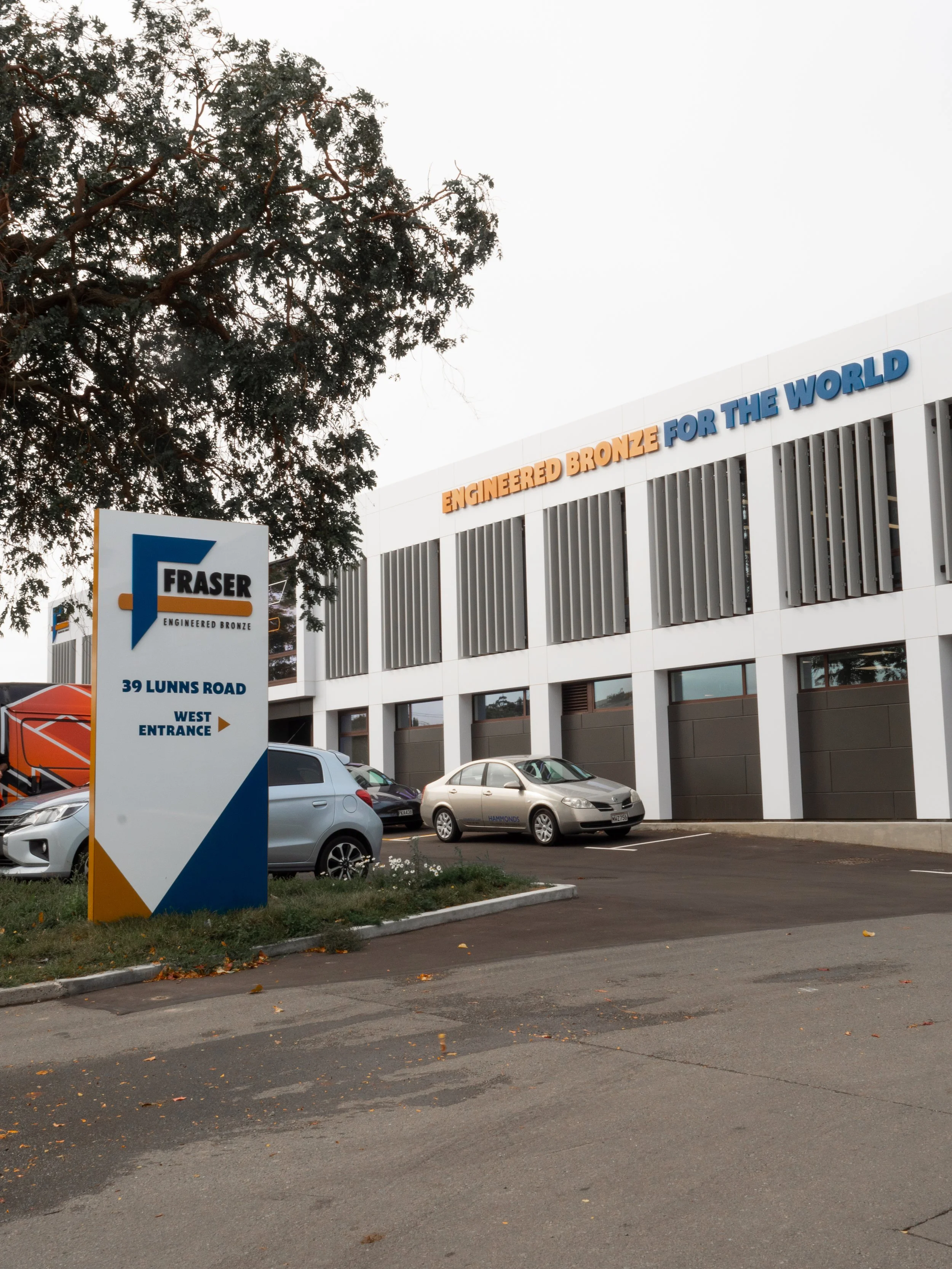 The Fraser Engineering building with parking lot and a sign indicating the west entrance at 39 Lunns Road.