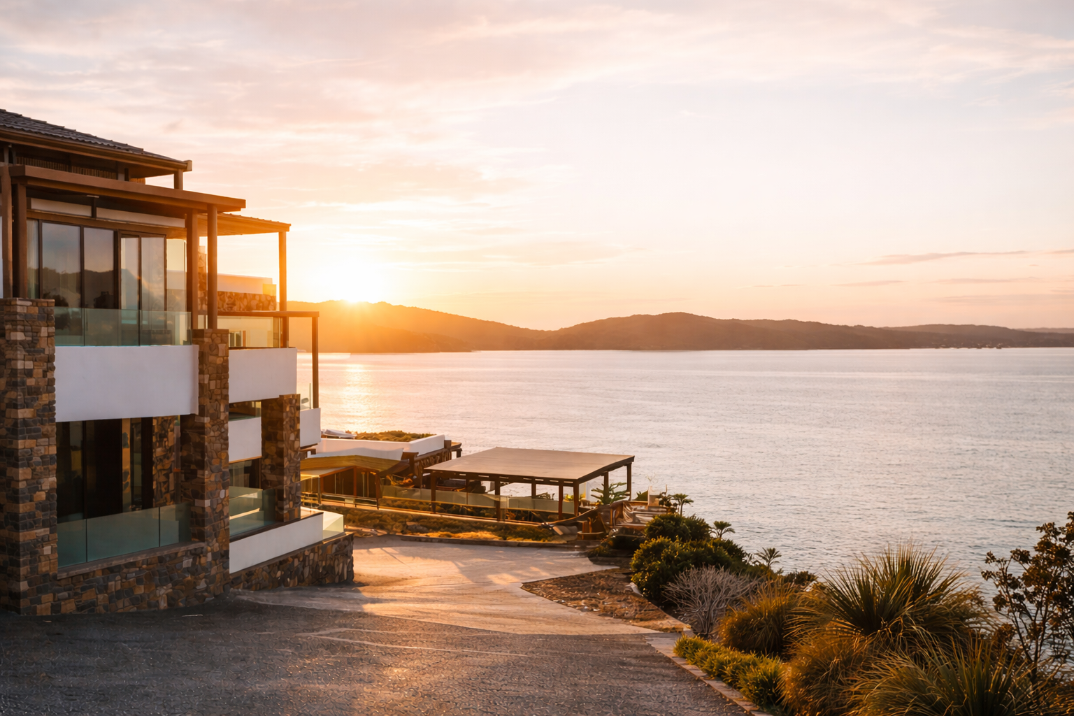 Sunset over a lake viewed from a modern house with large glass windows and stone accents.