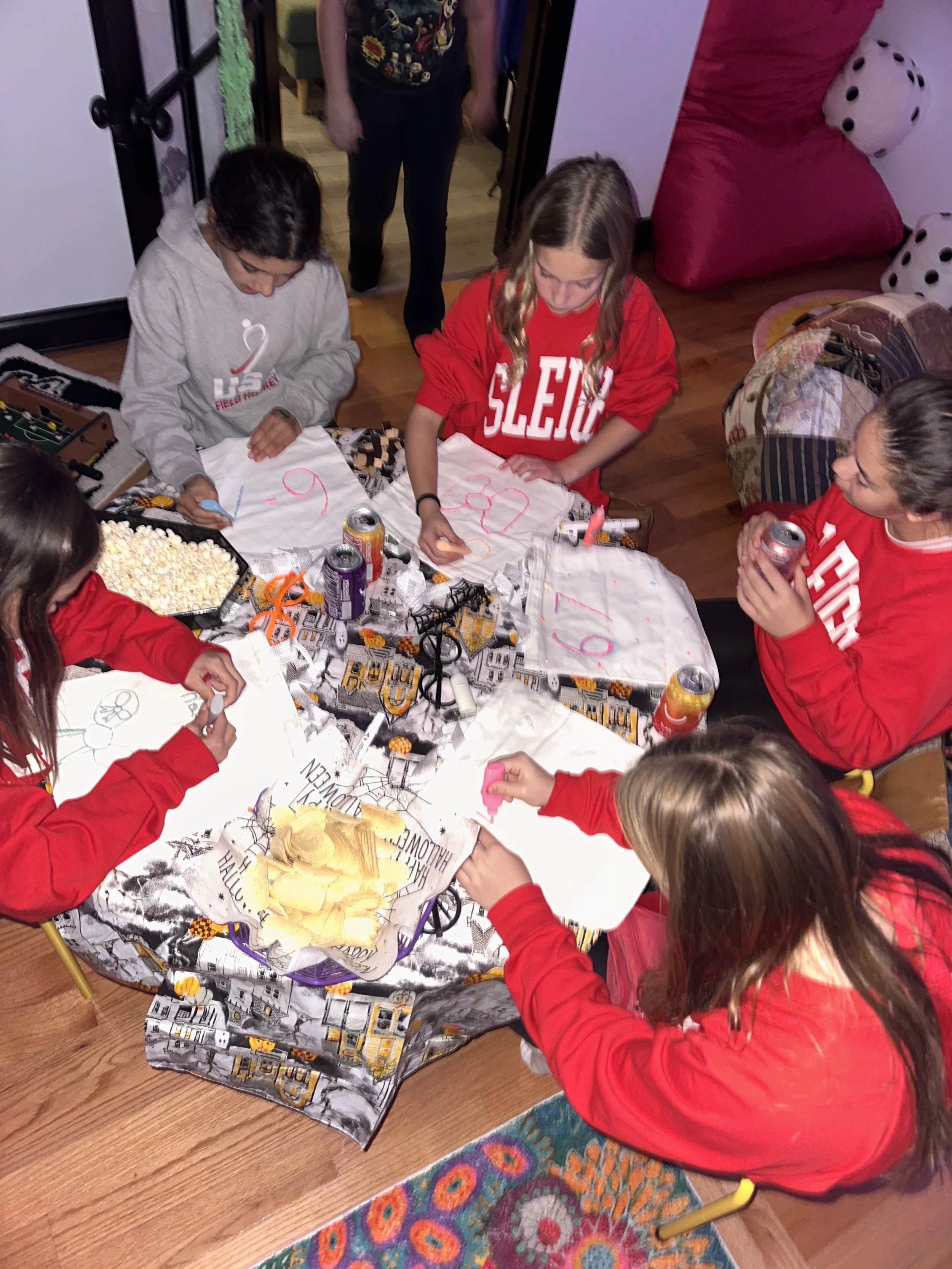 A group of tween girls laughing and chatting around the craft table during The Clubhouse Wellness Center’s Tween Halloween Bash in Phoenixville, PA — creative fun and friendship in a safe, social setting.