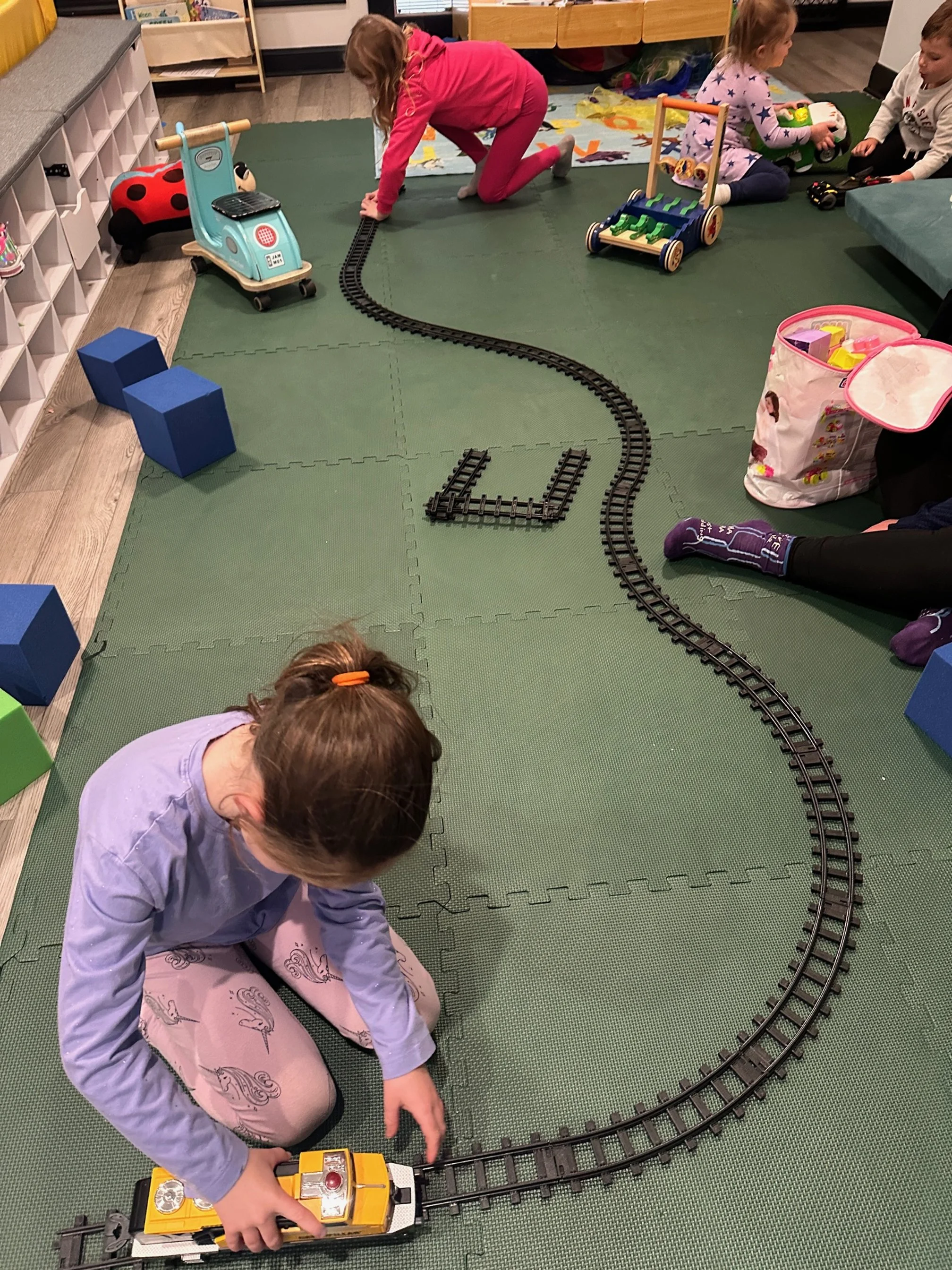 Toddler train set play on turf at The Clubhouse indoor play area Phoenixville PA near Spring City