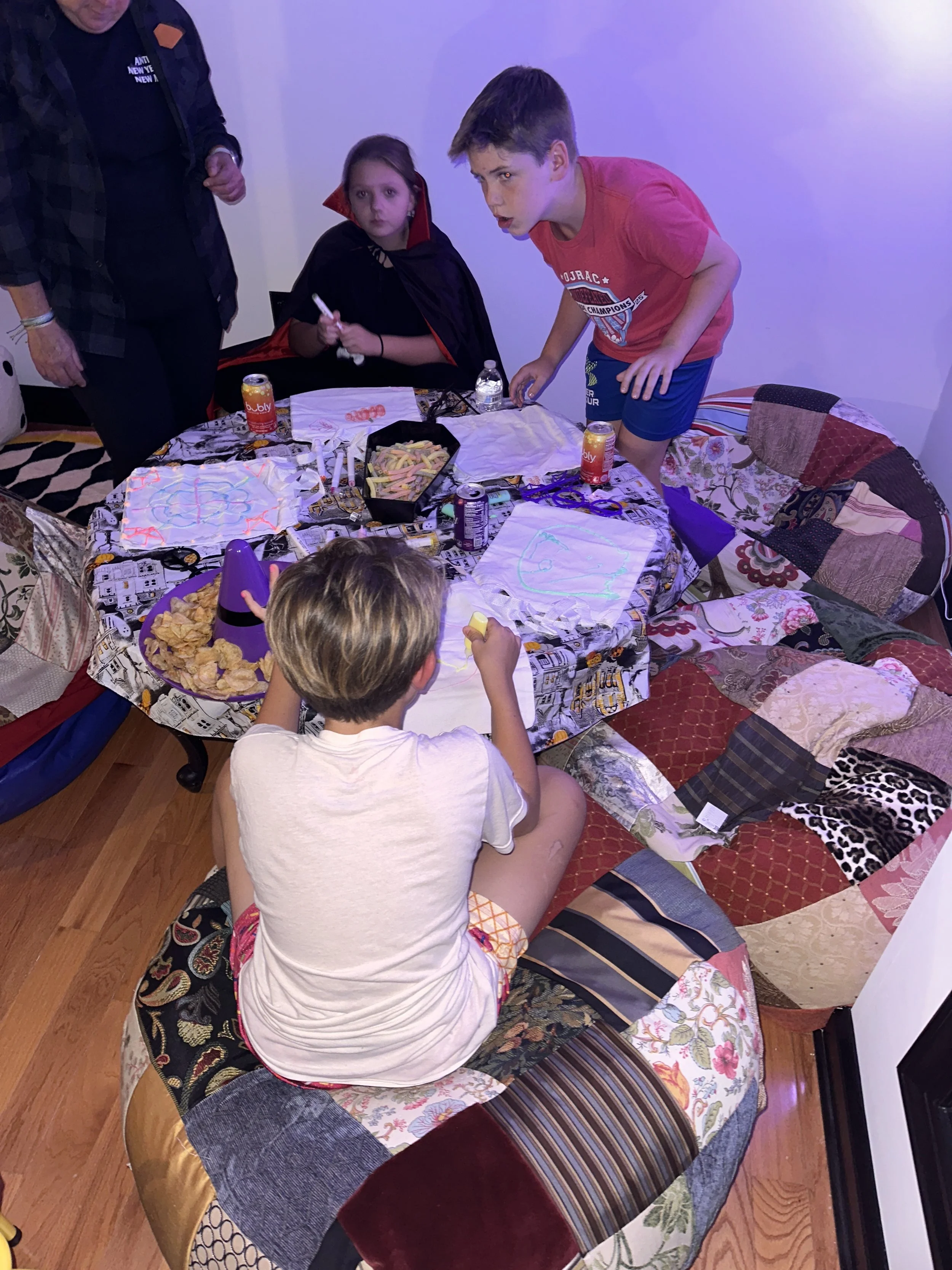 A group of kids painting Halloween designs together during The Clubhouse Tween Bash — creative expression and teamwork in a festive after-school environment.